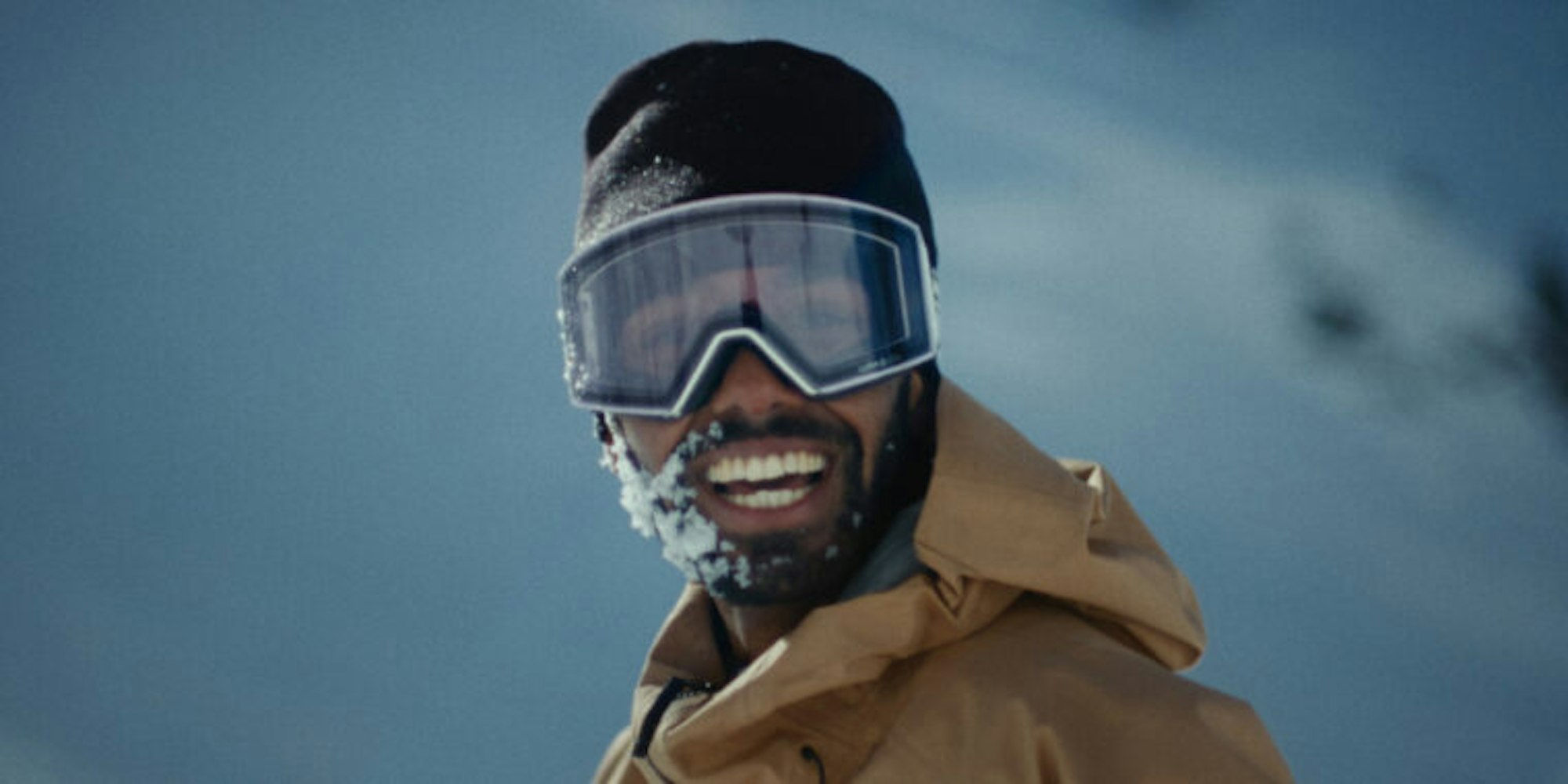 Dennis Ranalter smiles at the camera with a hat and ski goggles on