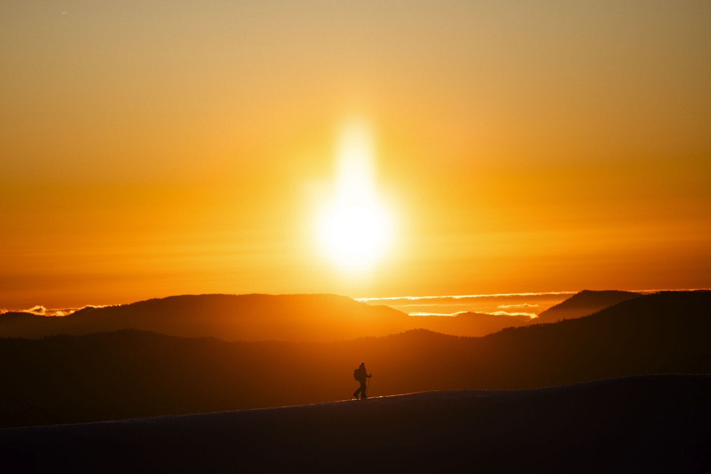 Hiker walking along a mountain ridge at dusk