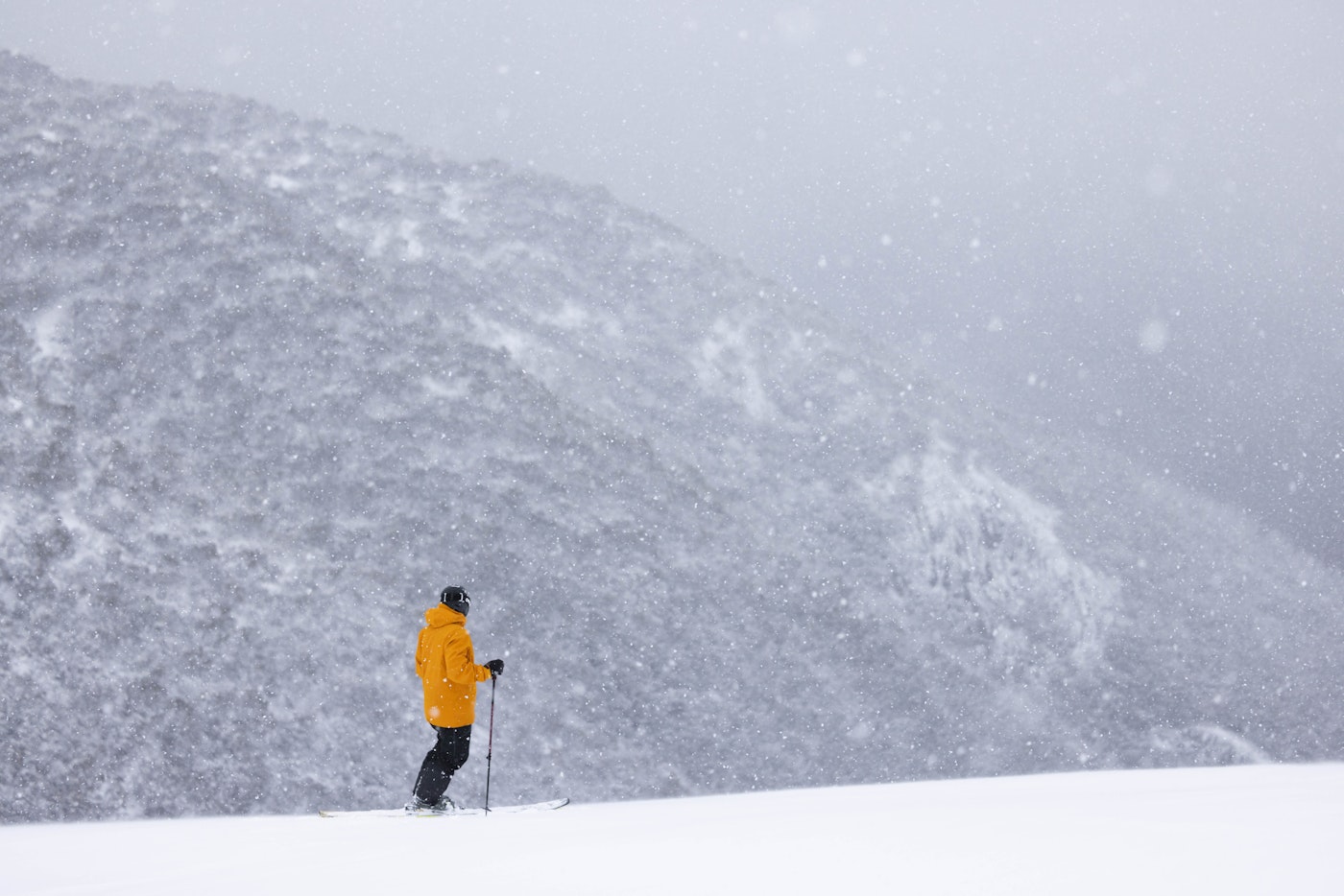Skier stands on the side of a mountain in a blizzard