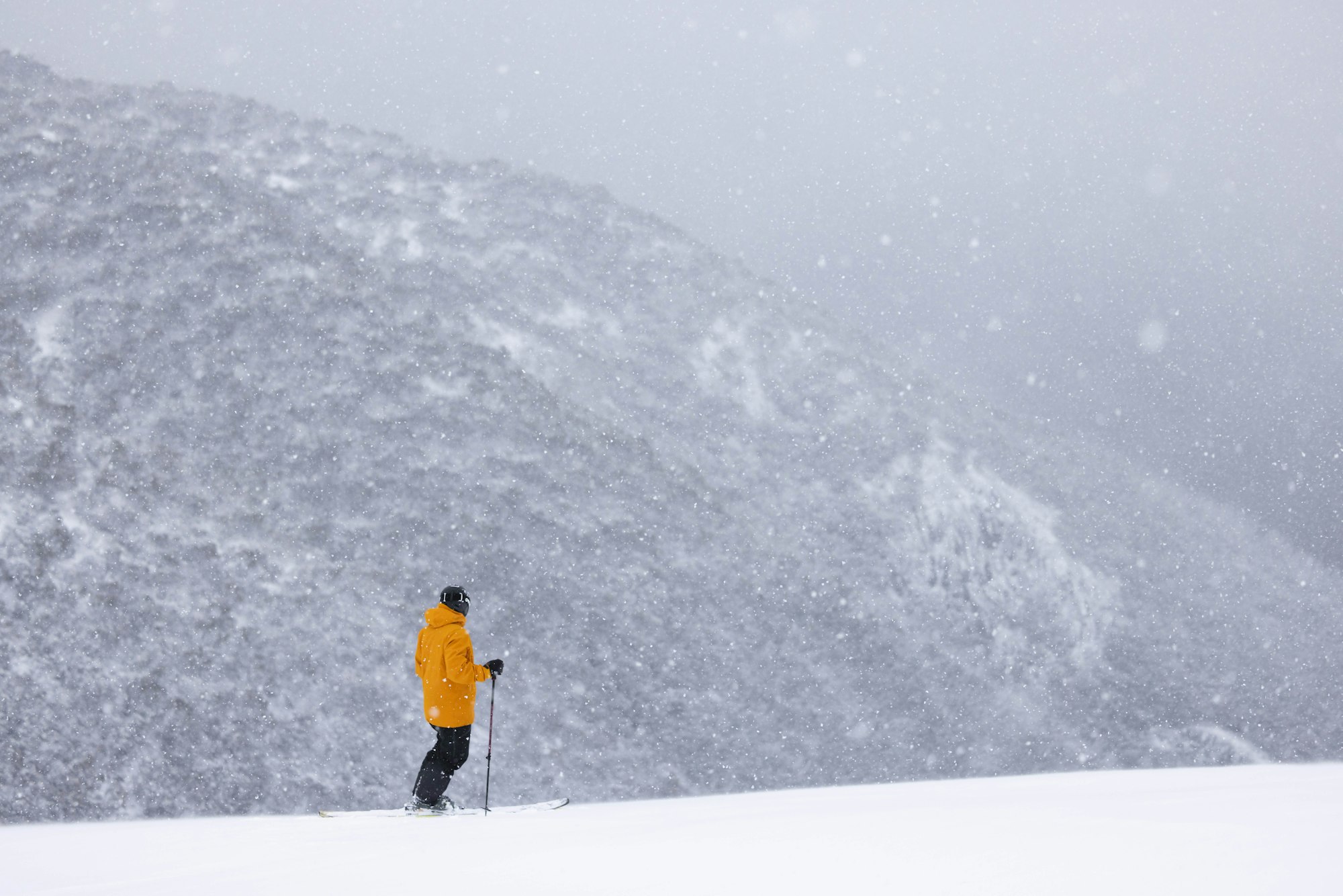 Skier stands on the side of a mountain in a blizzard