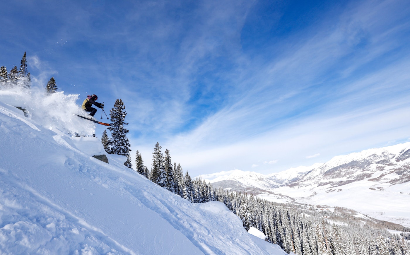 Skier jumping off a rock in deep snow at Crested Butte Mountain Resort