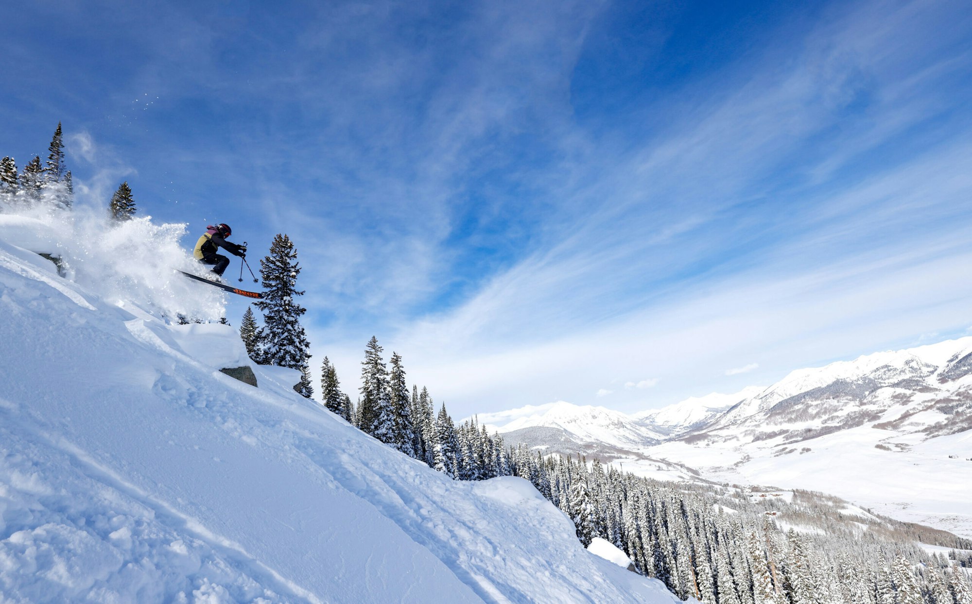 Skier jumping off a rock in deep snow at Crested Butte Mountain Resort