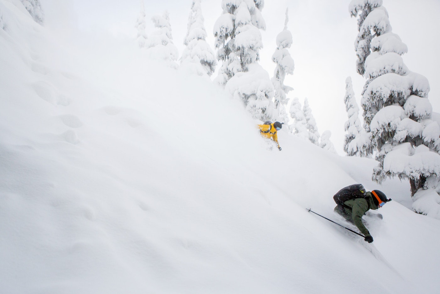 Two skiers Ian Morrison and Abel Moga skiing through deep snow in the forest at Shames mountain