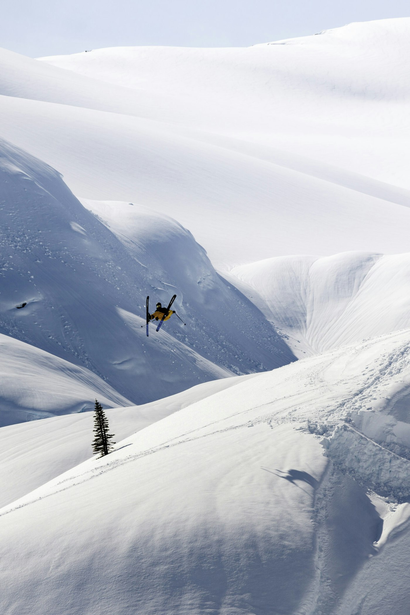 Skier Jonathan Rollins flipping off a jump on skis on a snowy mountain in Pemberton, BC