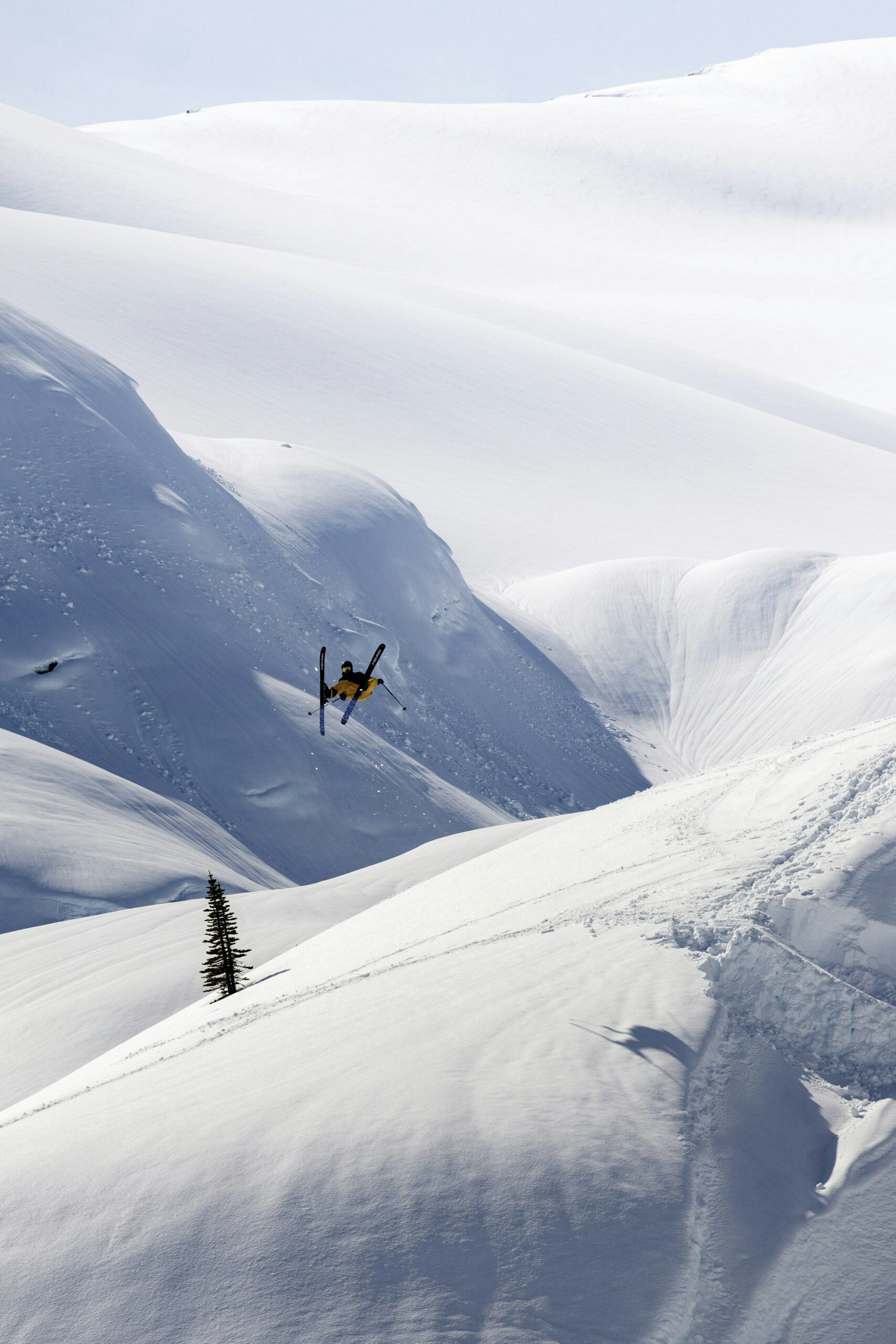 Skier Jonathan Rollins flipping off a jump on skis on a snowy mountain in Pemberton, BC