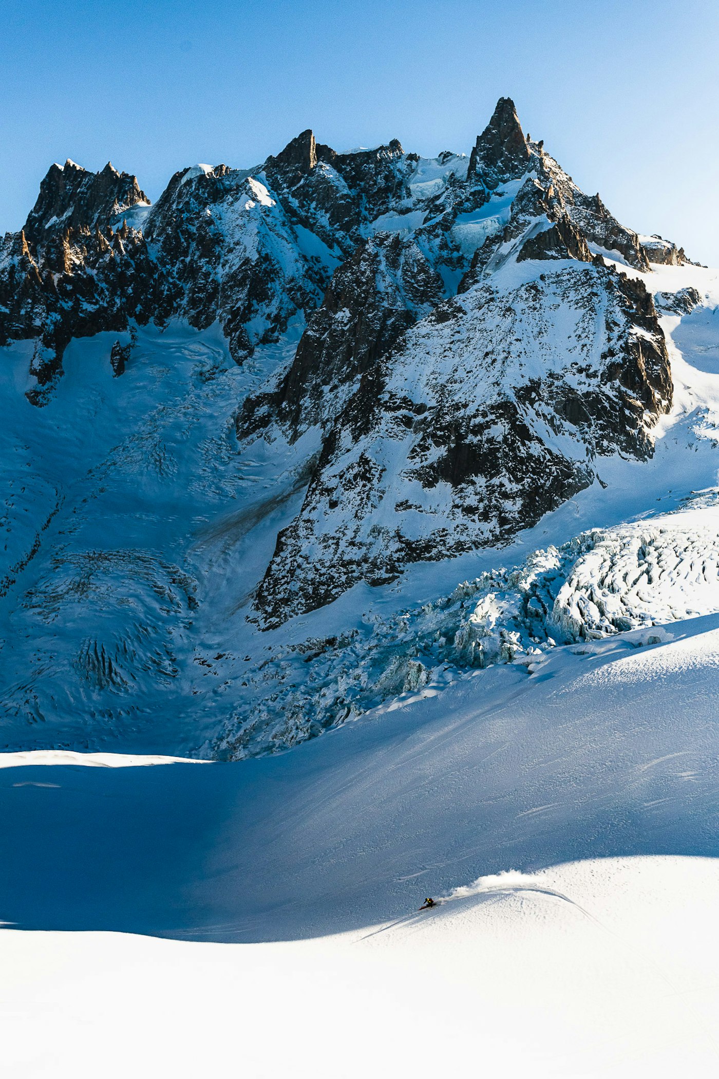 Skier Bine Zalohar turning through deep snow in a basin below high peaks in Chamonix, Fra