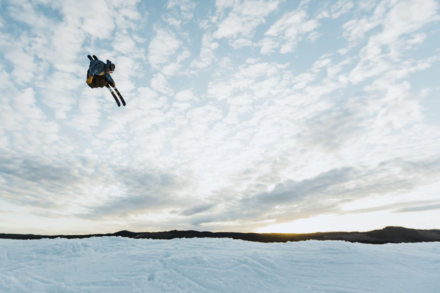 Skier Benjamin Carlund flying through the air on skis at dusk
