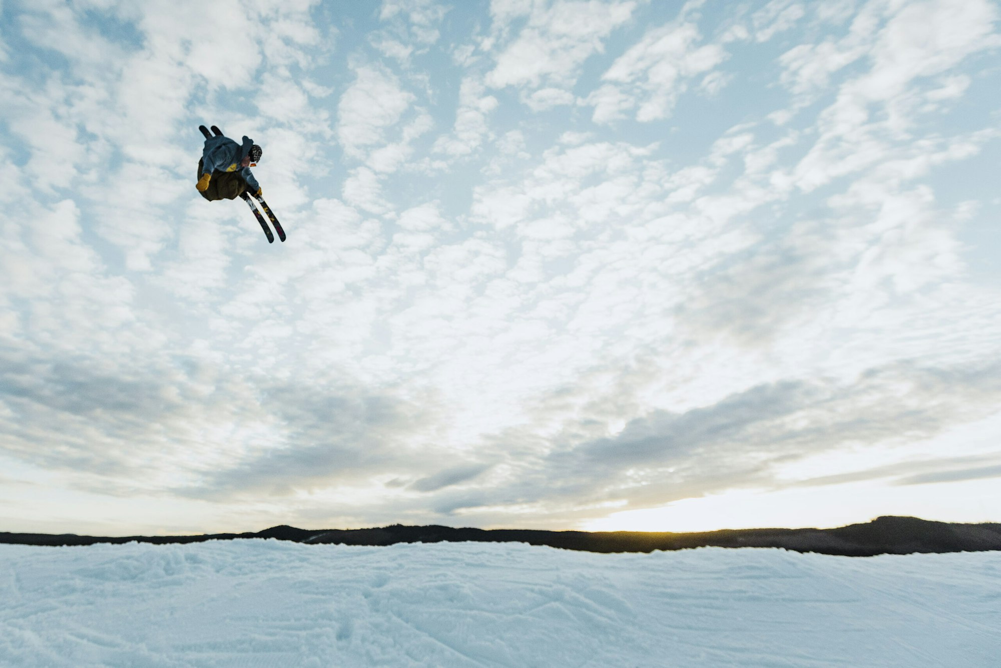 Skier Benjamin Carlund flying through the air on skis at dusk
