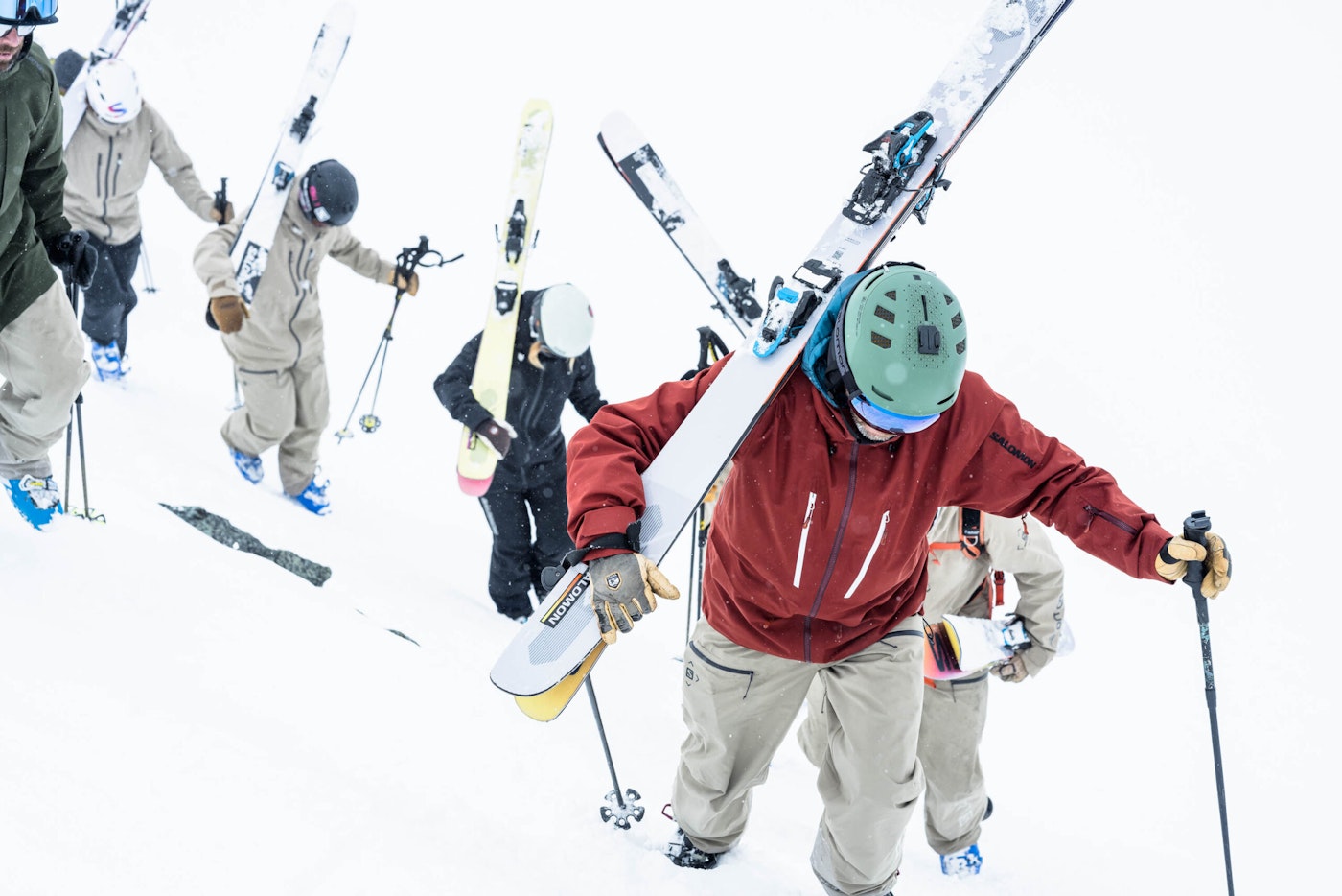 Skiers Mike Douglas and the Salomon Junior Men Collective hiking up a snowy ridge with their skis