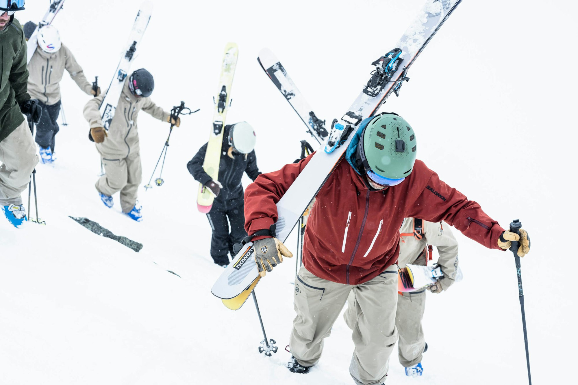 Skiers Mike Douglas and the Salomon Junior Men Collective hiking up a snowy ridge with their skis