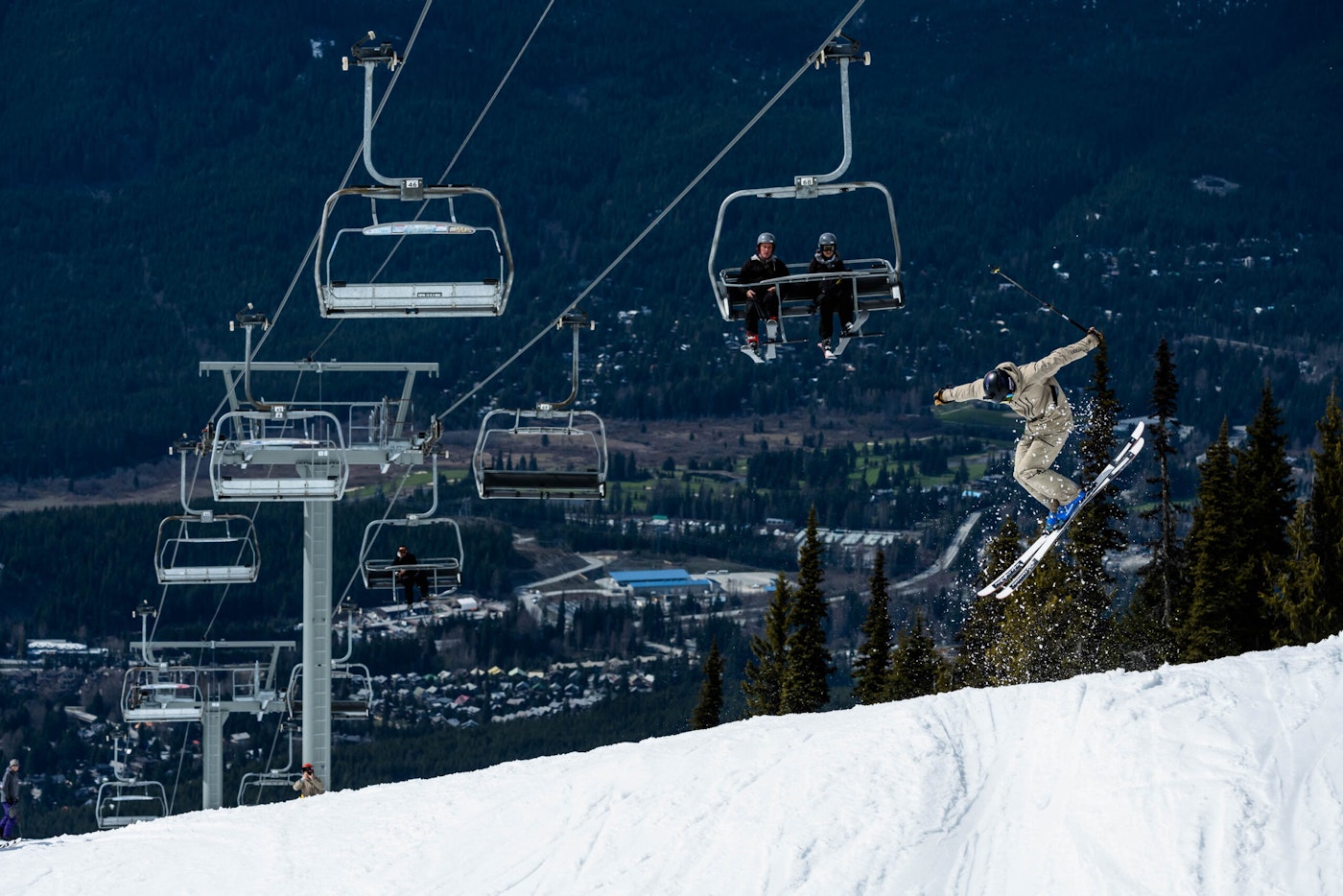 Skier Wyatt Gentry jumping through the air on skis under a chairlift