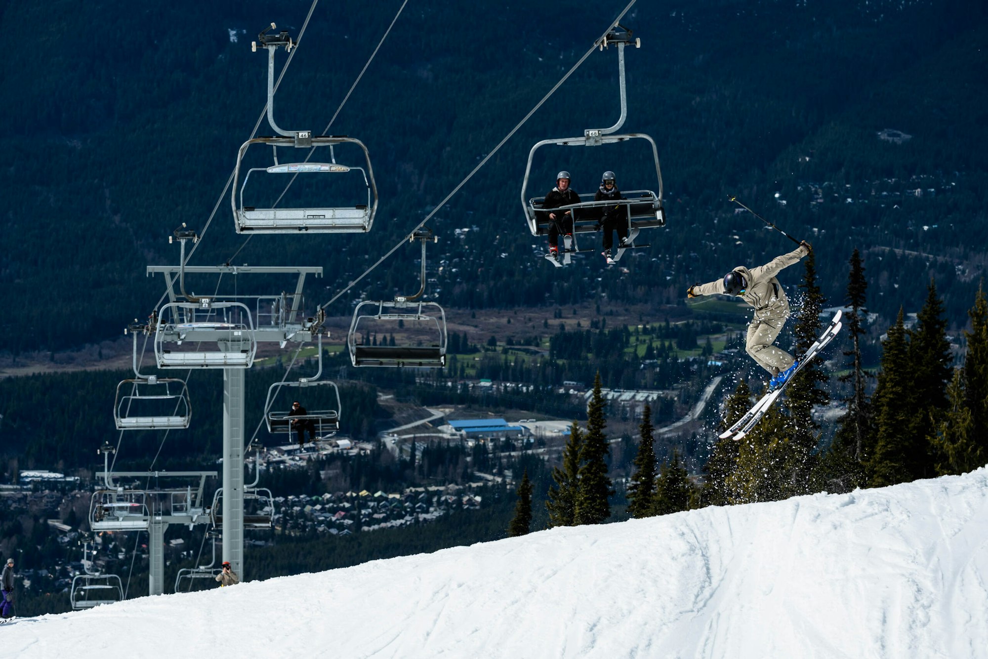 Skier Wyatt Gentry jumping through the air on skis under a chairlift