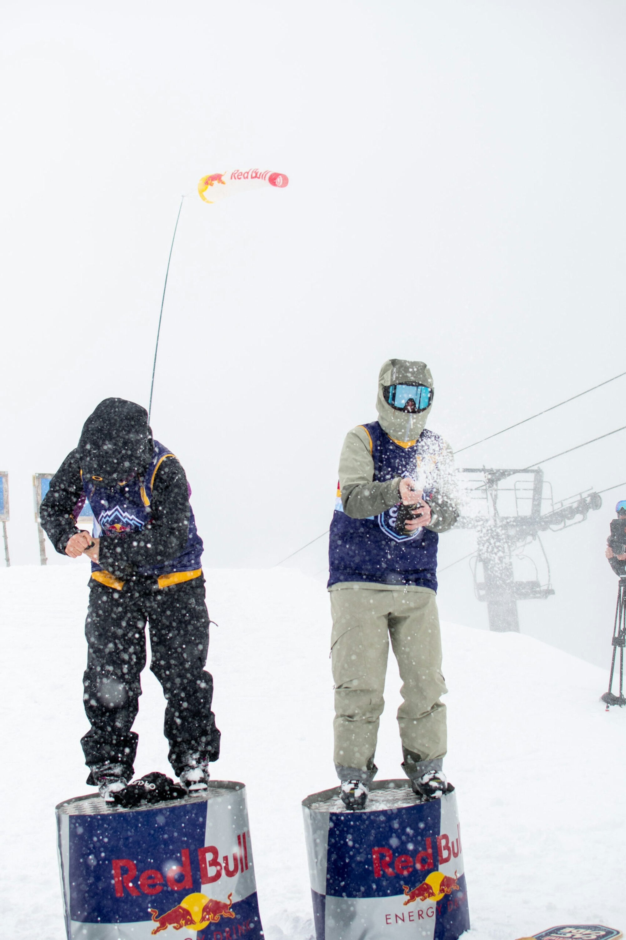 Grace Henderson and Caroline Claire spray champagne from the Red Bull Cascade podium in the snow