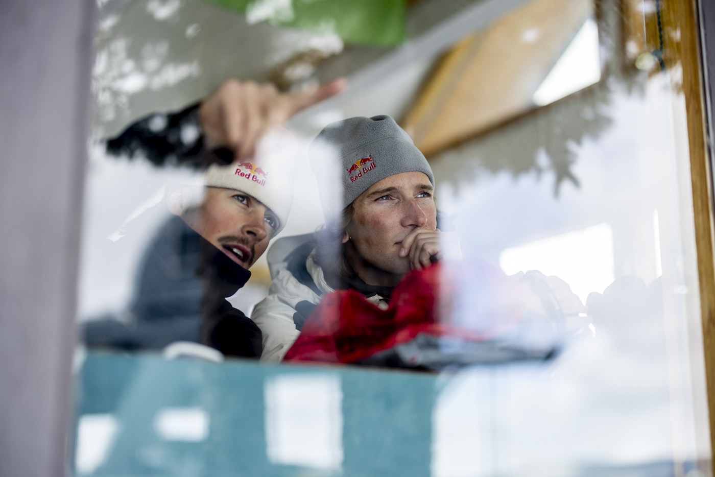 Birk Irving and Torin Yater-Wallace through a window pointing outside