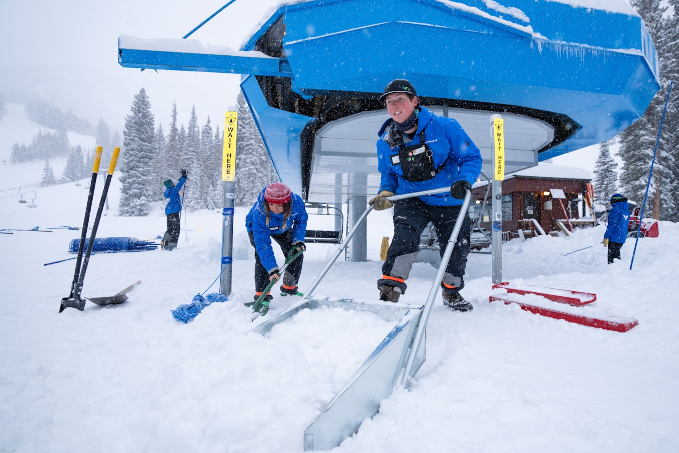 Snowbird lift employees shovel snow away from the base of a chairlift at Snowbird resort