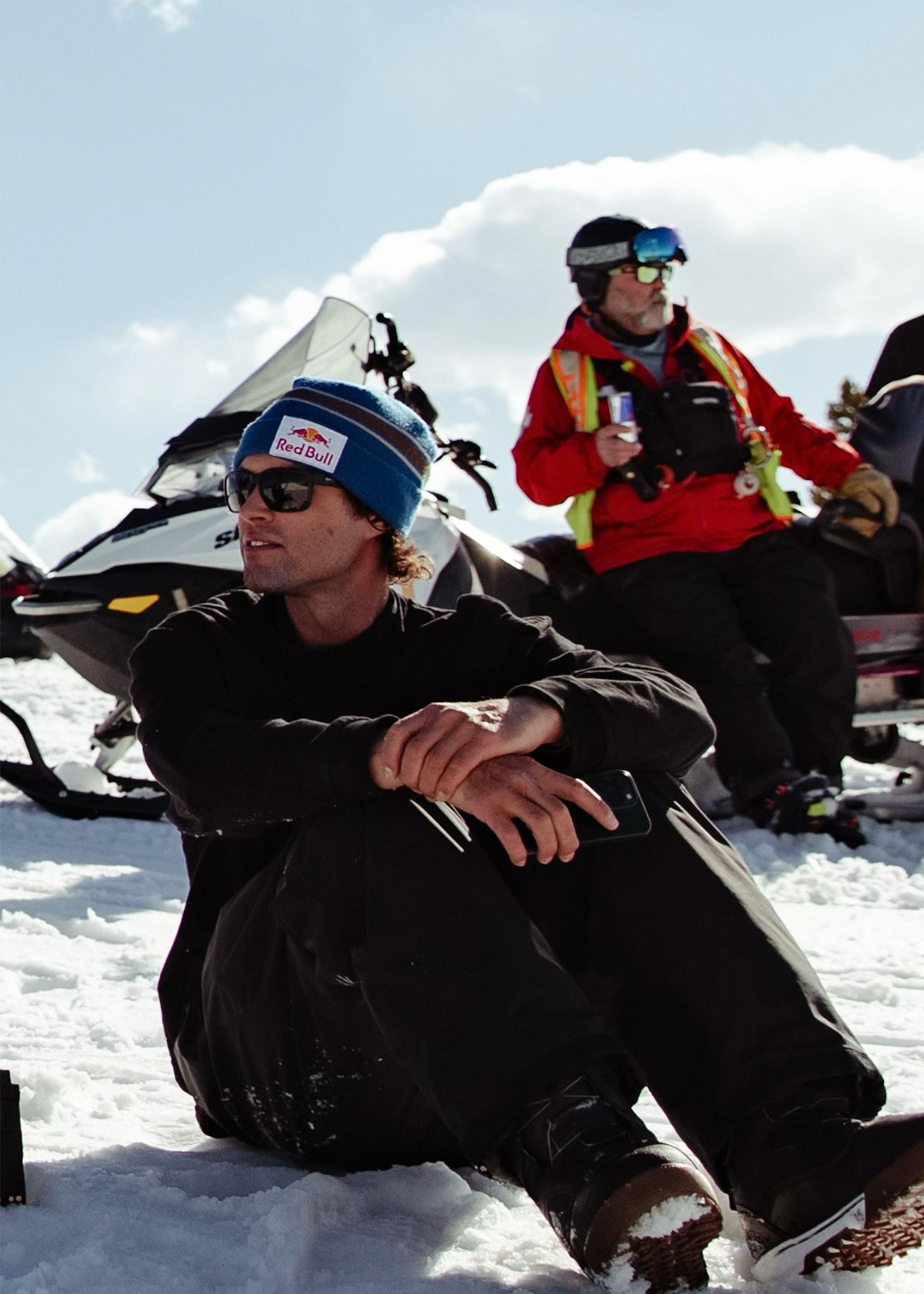Bobby Brown sitting on the snow with a ski patroller