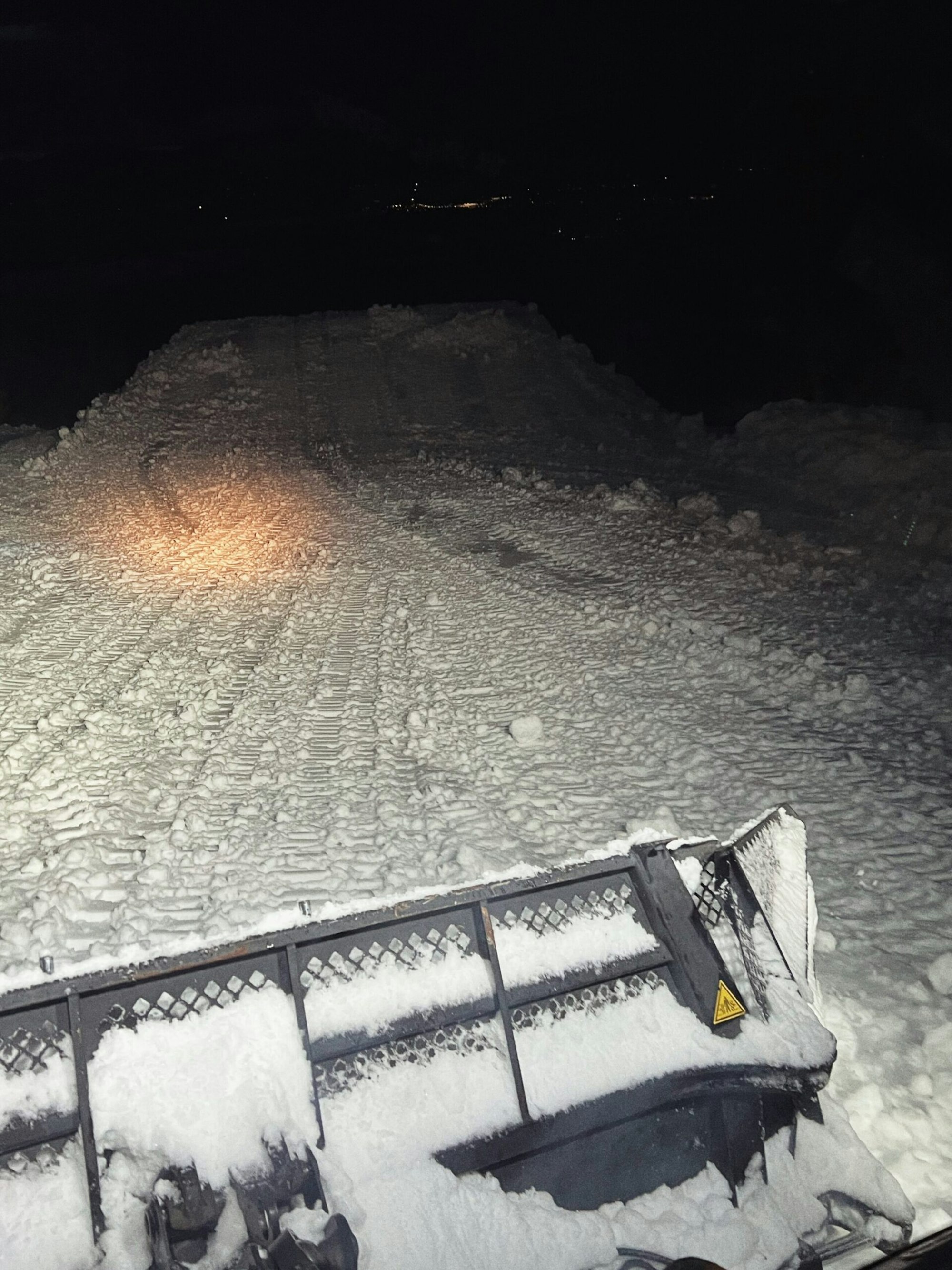 A snowcat at night in the dark working or terrain park features