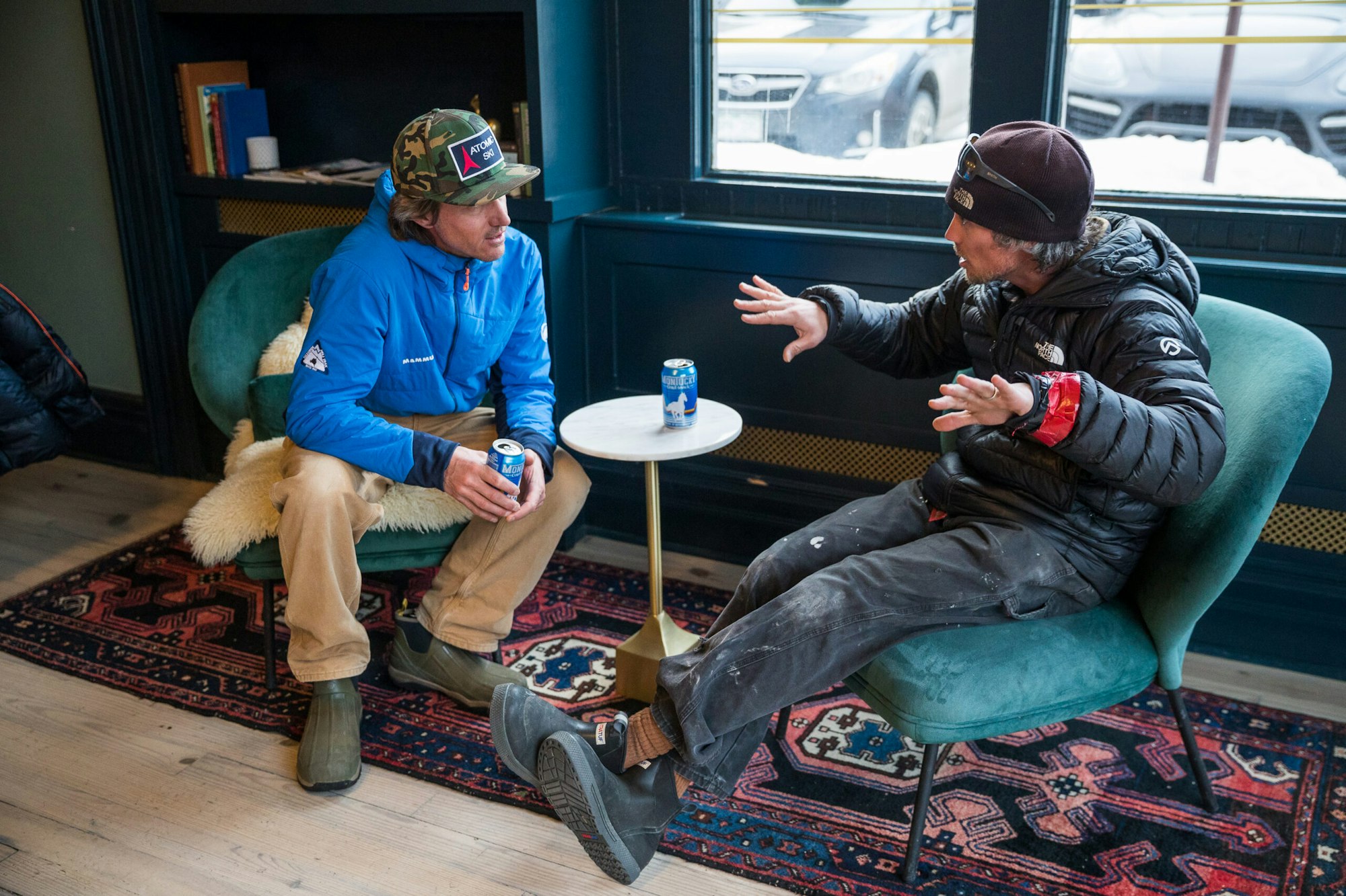 Ski guides sit on chairs inside debating while drinking beers