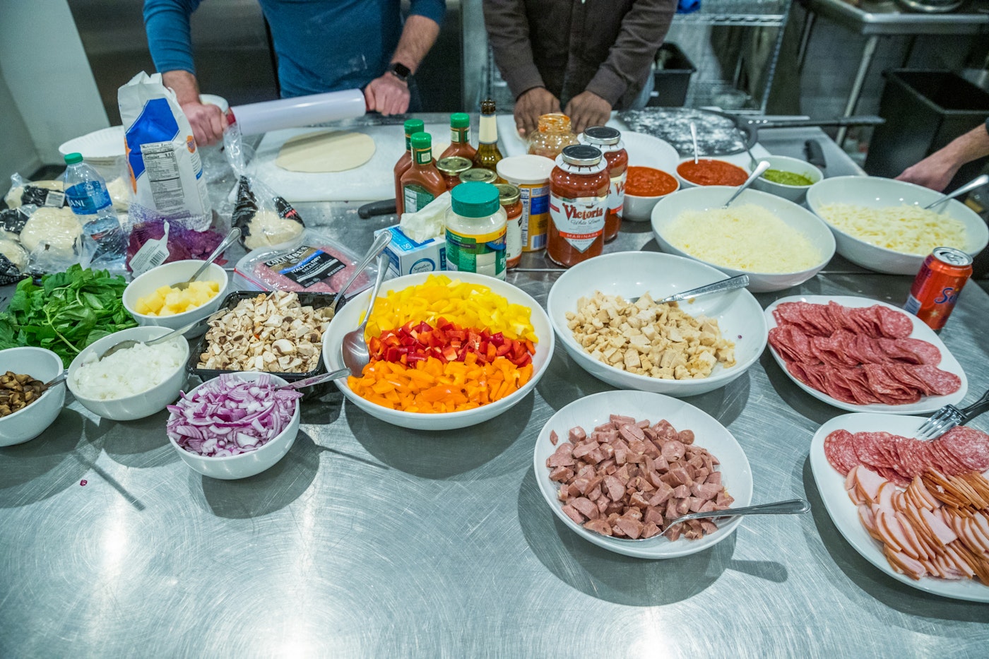 Food being prepped for cooking on a silver table in an industrial kitchen