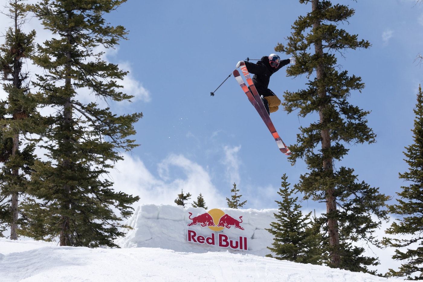 Skier mid air off a Red Bull jump grabbing tails of skis