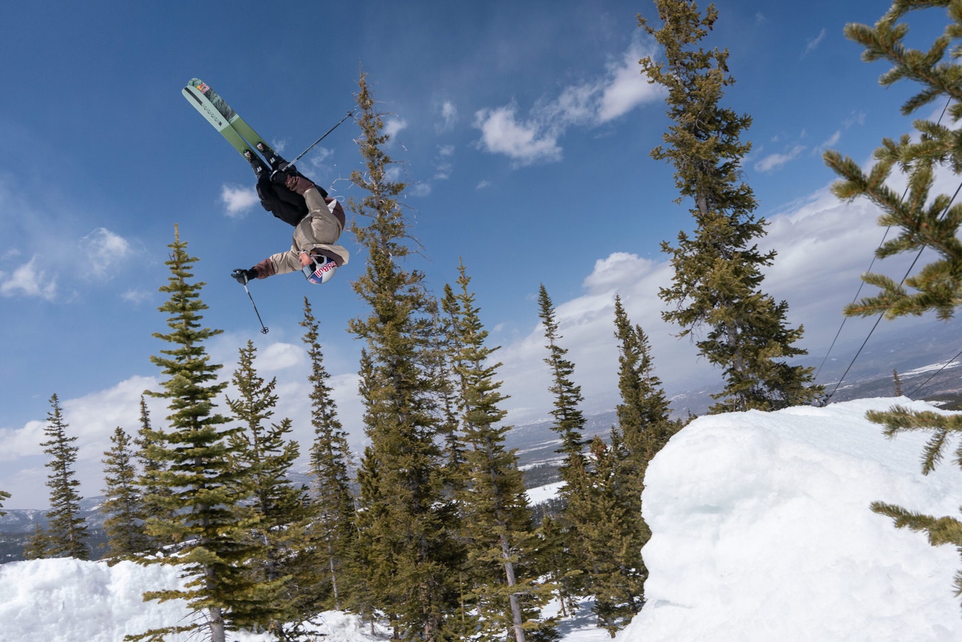 Skier upside down off a snow jump in the woods