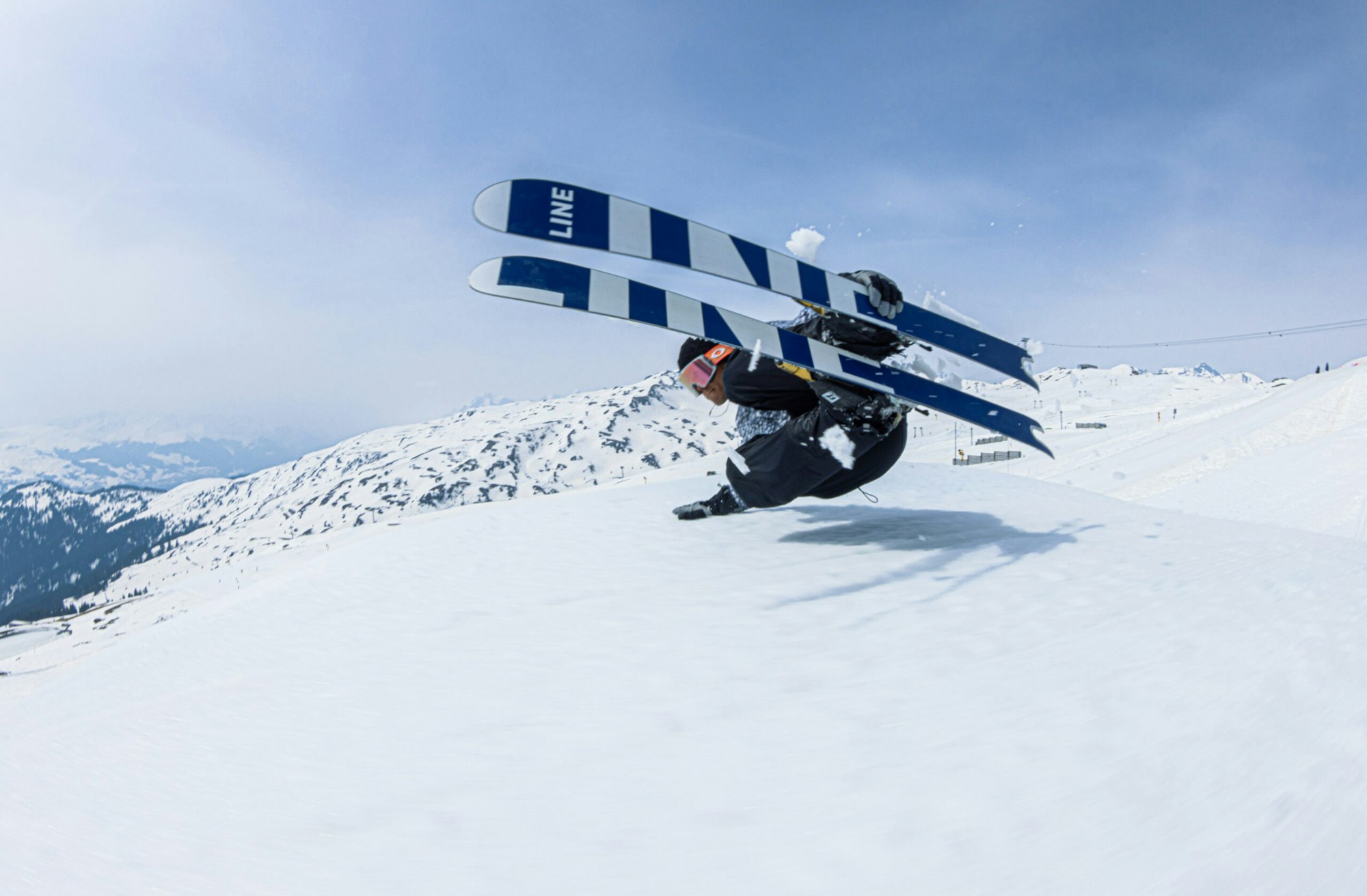 Skier sideways mid air off a booter jump grabbing the side of their skis