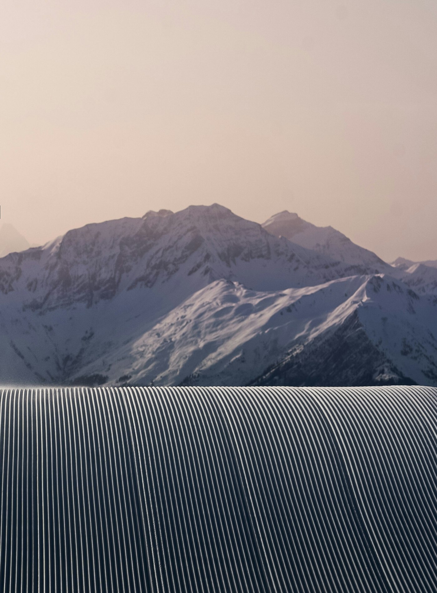 Perfectly groomed ski trail overlooking mountains at dusk