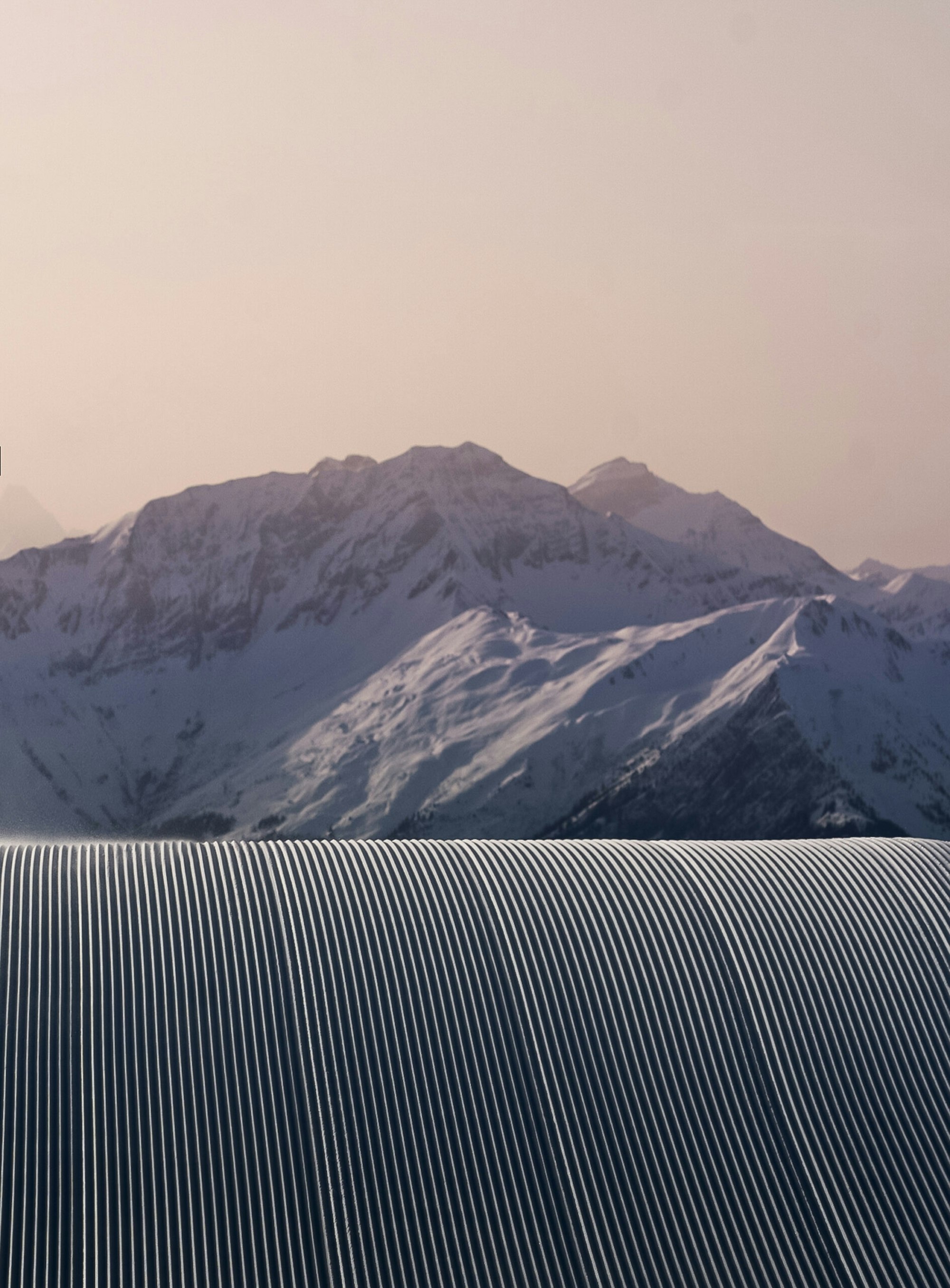 Perfectly groomed ski trail overlooking mountains at dusk