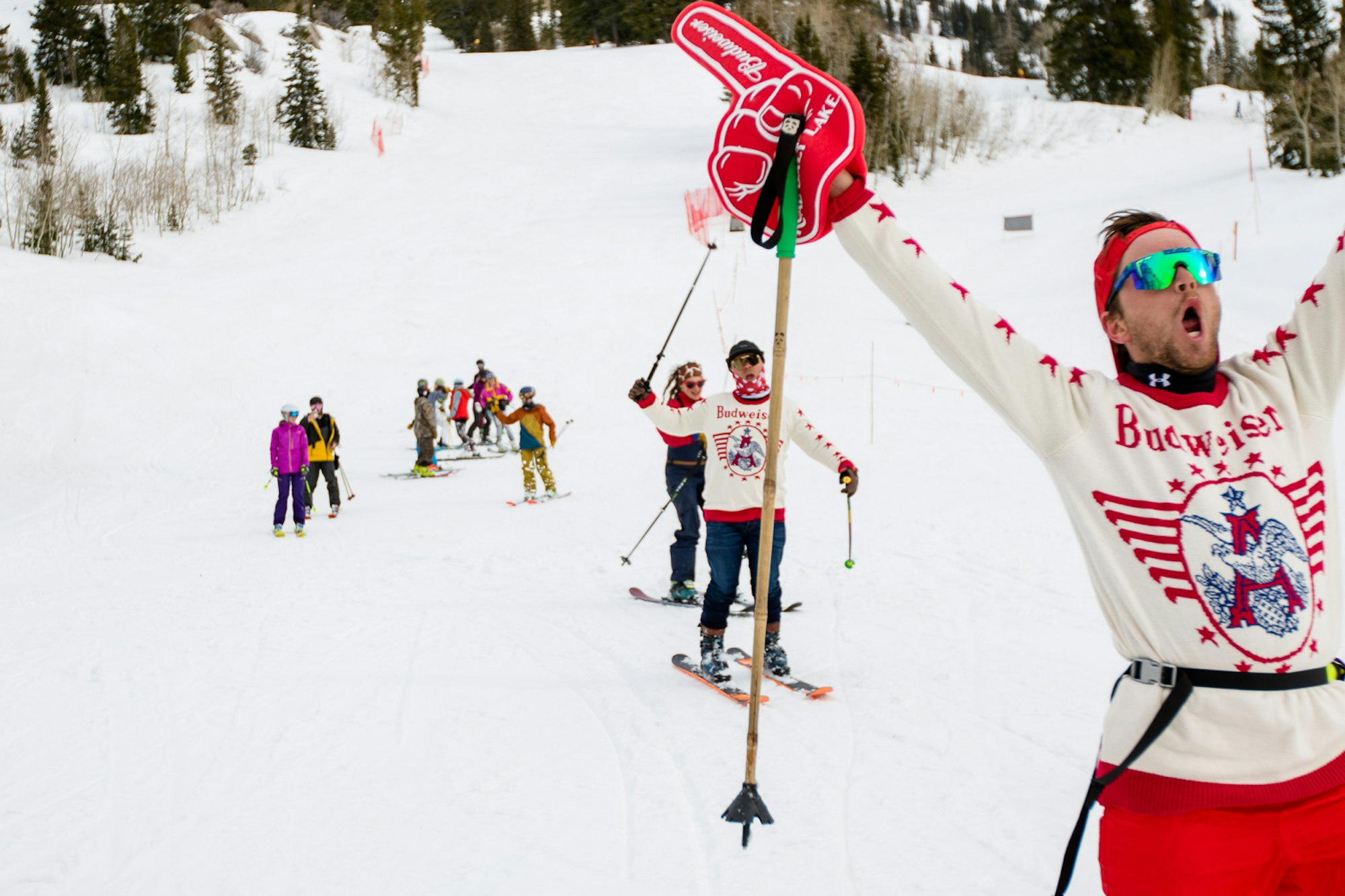 Skiers in Budweiser Sweaters ski down with their hands up