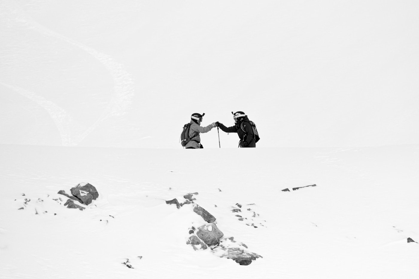 2 Skiers fist bump on a snowy mountain ridge