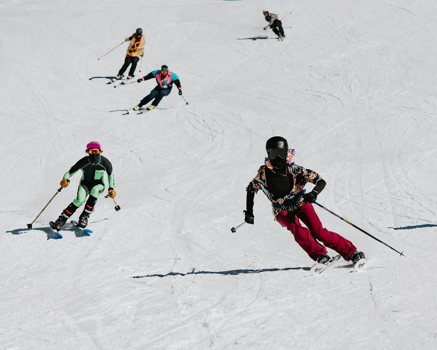 Skiers in costumes ski down a snowy slope