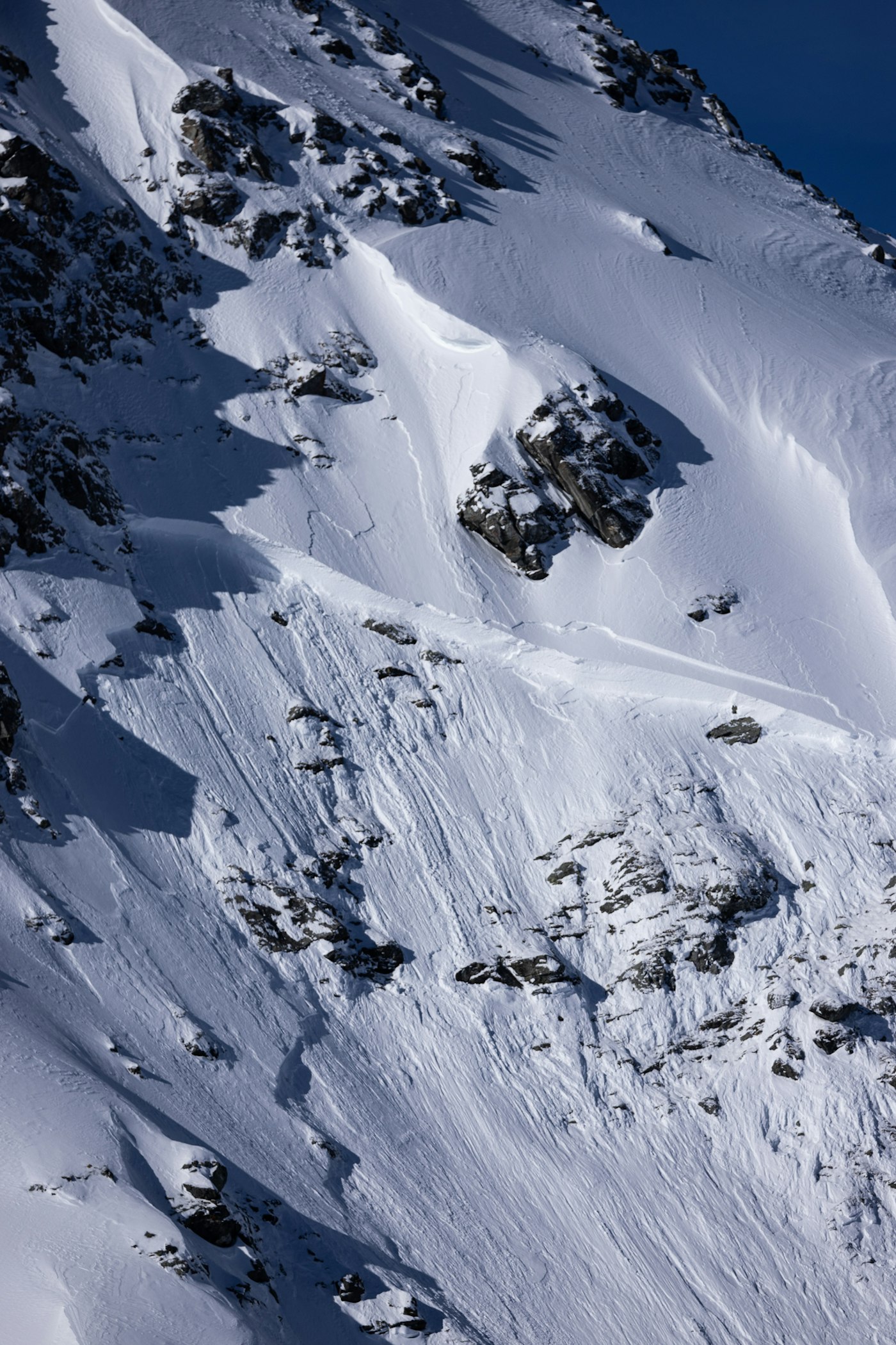 An avalanche on the side of a rocky, snow mountain