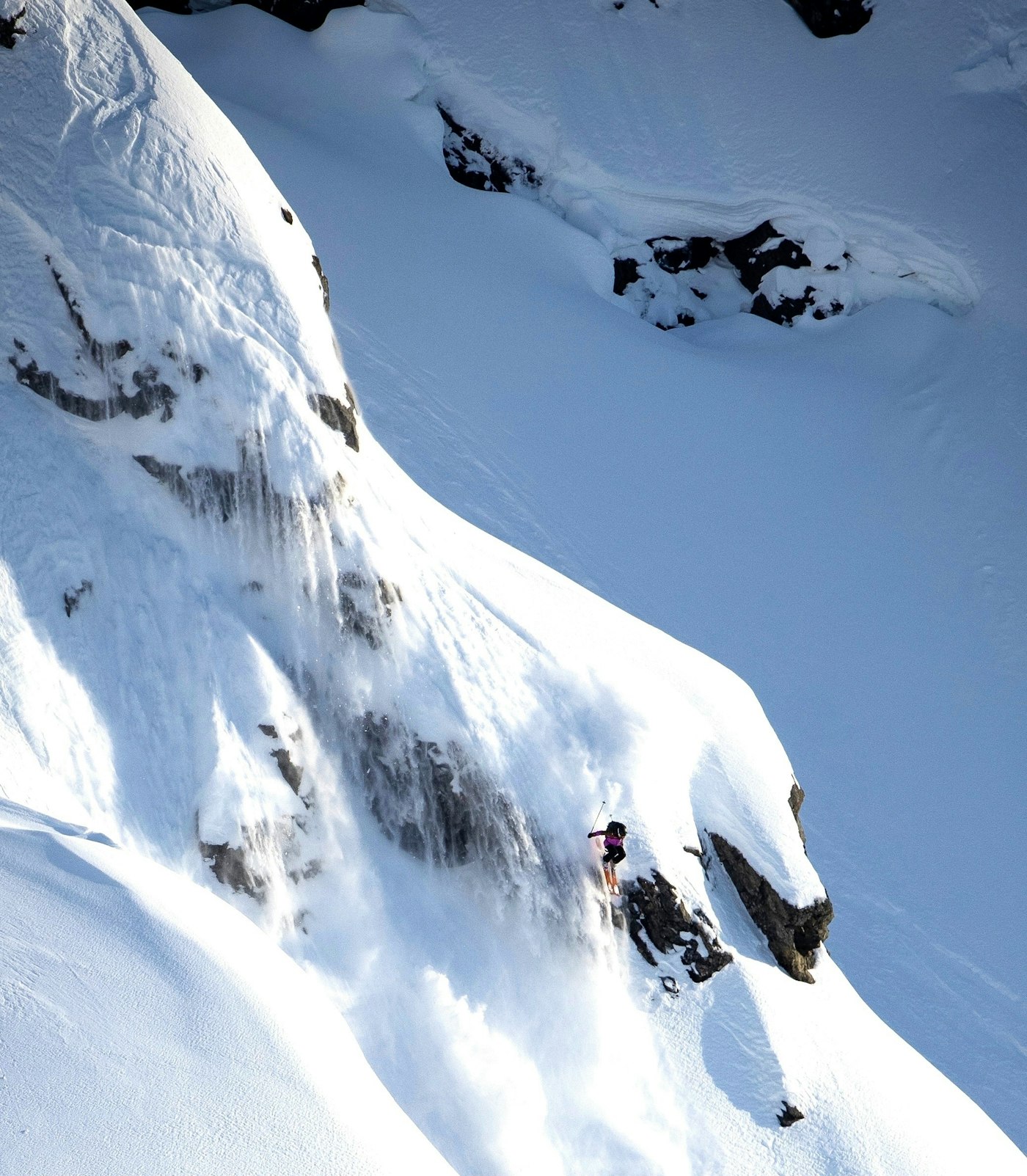 Caite Zeliff dropping a huge cliff on skis with stuff behind her