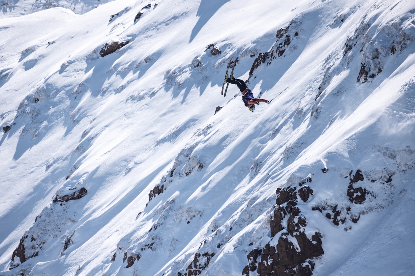 Freeride world tour skier flipping off a rock into snow