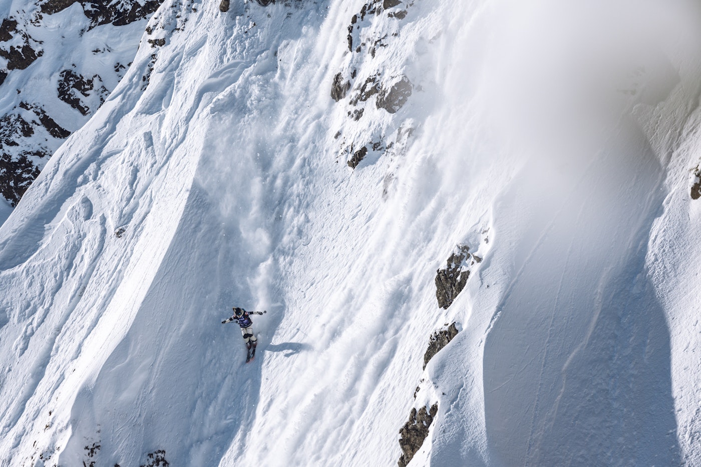 Freeride World Tour skier skiing down a rocky snowy face
