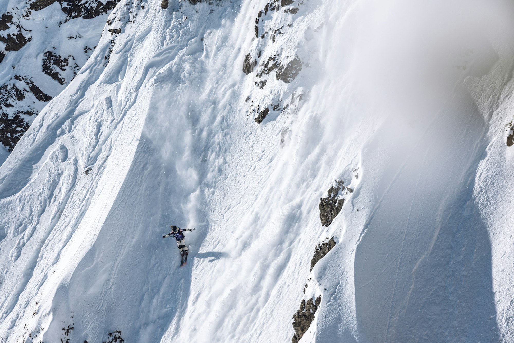 Freeride World Tour skier skiing down a rocky snowy face