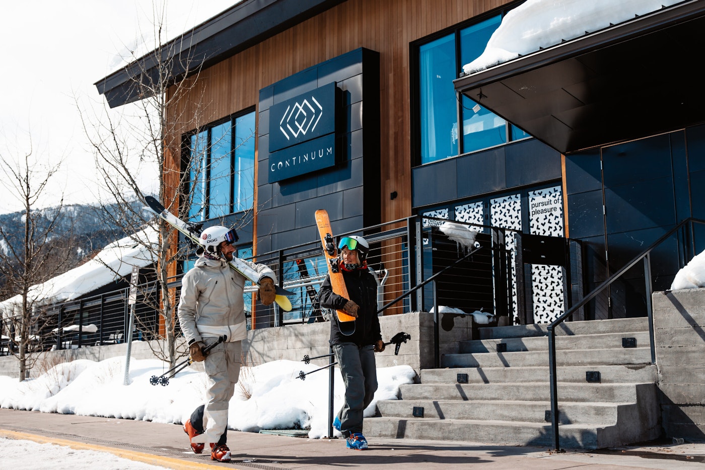 Skier walking on a sidewalk with their skis
