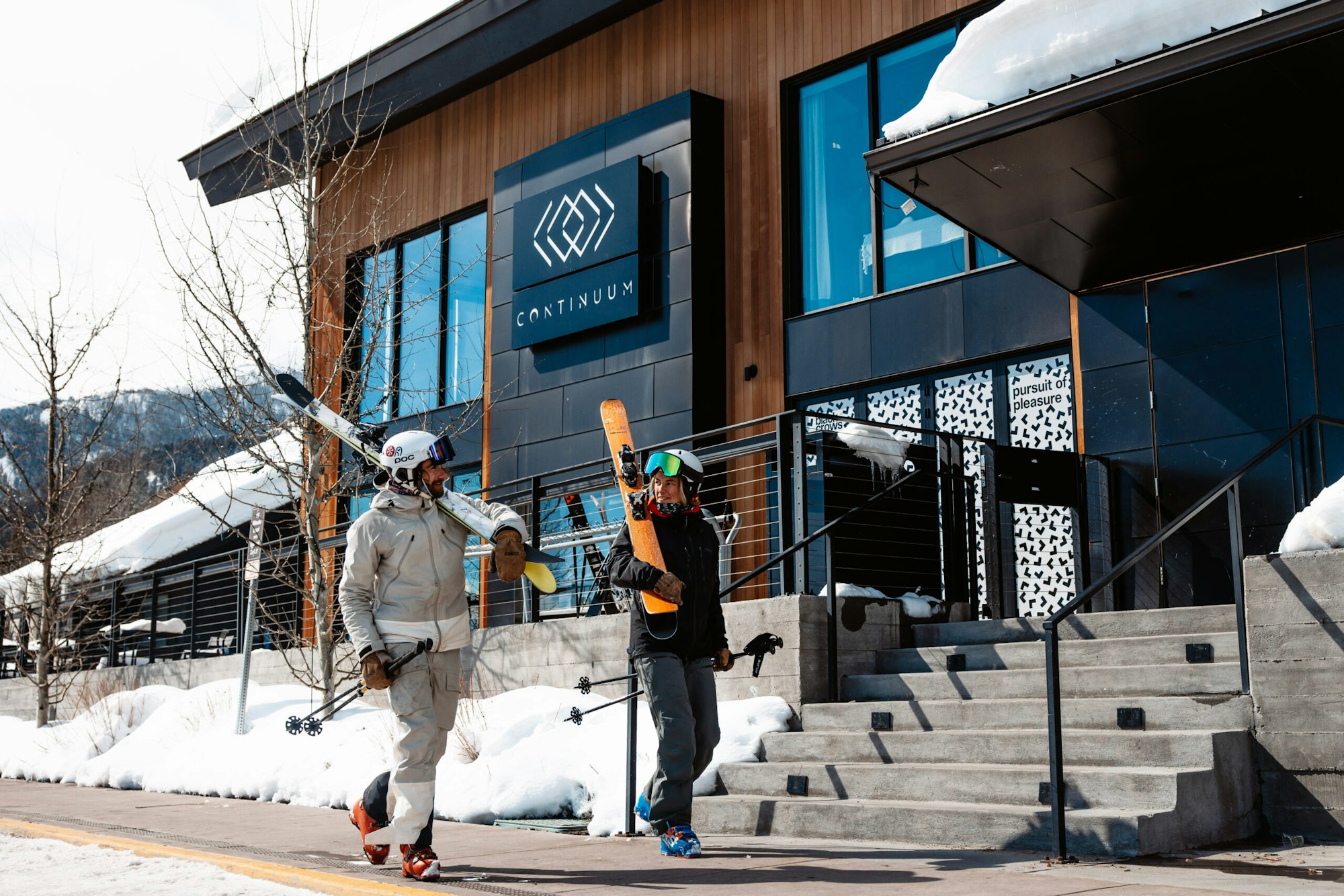 Skier walking on a sidewalk with their skis