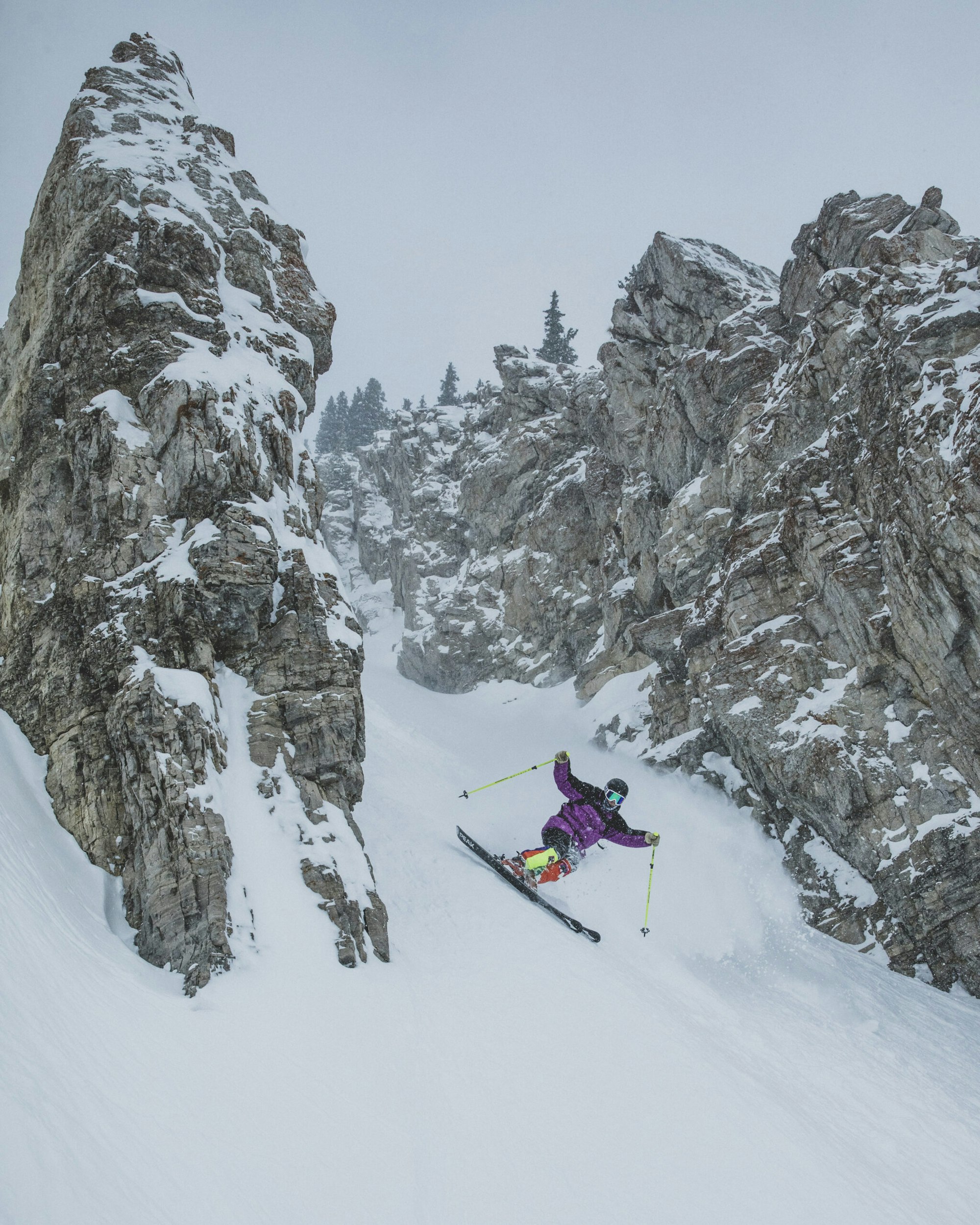 Skier turns down rocky couloir in a blizzard