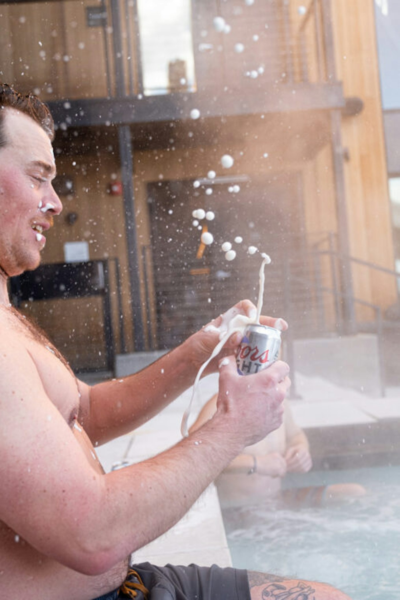 Man cracks open a car of Coors Light at a hot tub