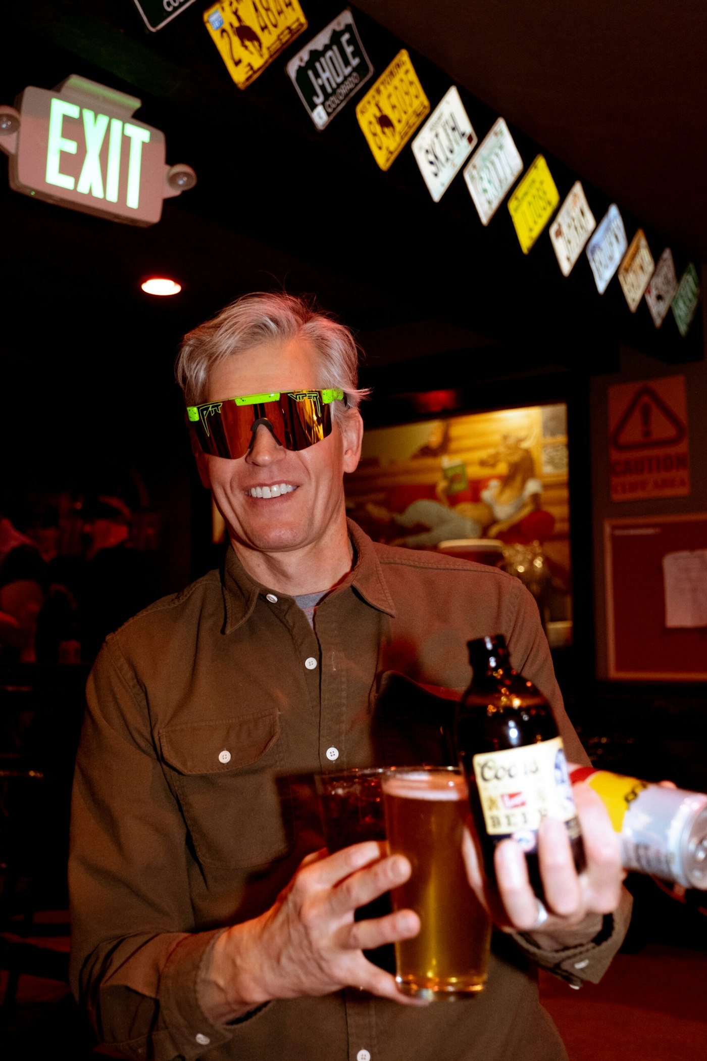 Man holding a lot of beers with sunglasses on in a bar