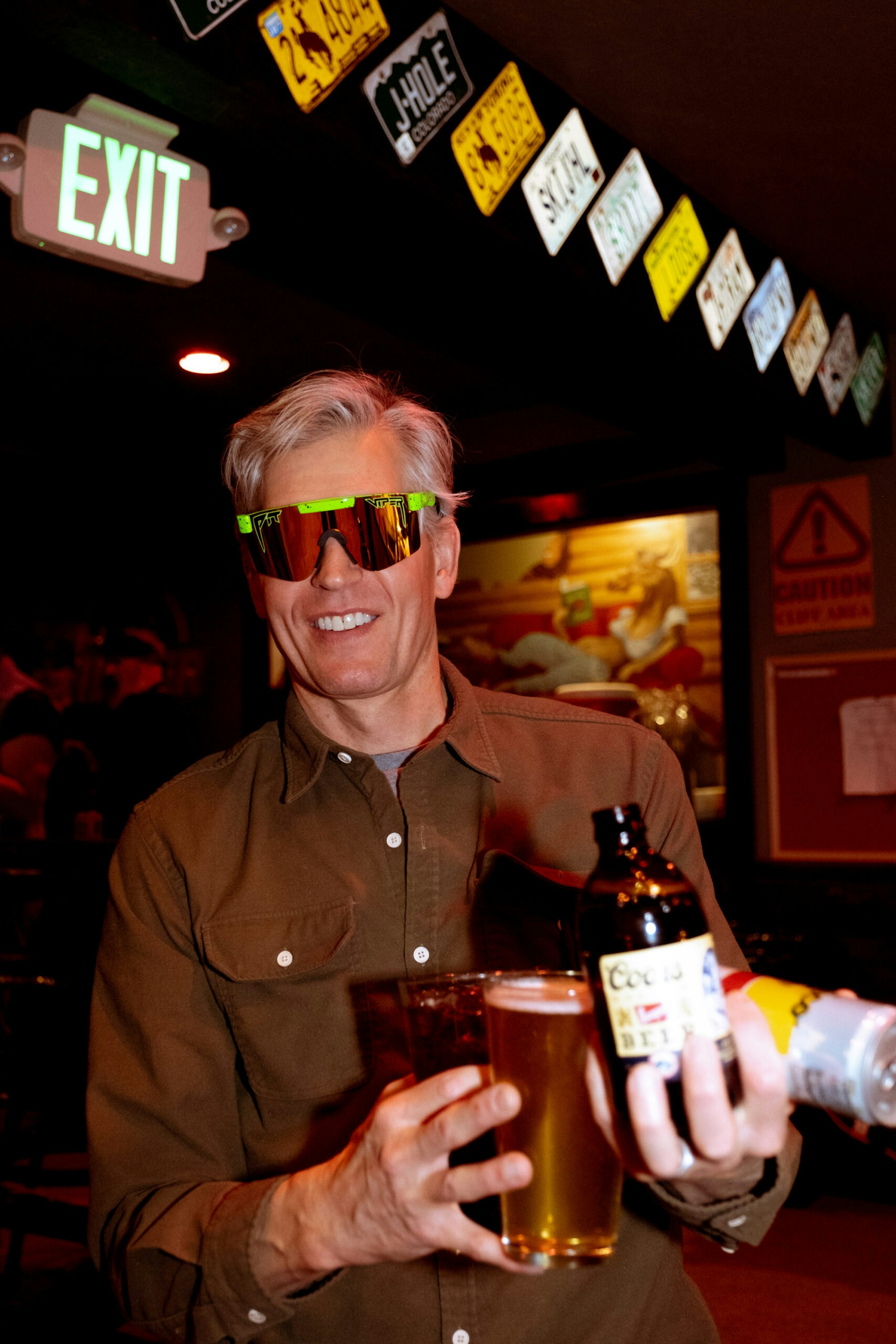Man holding a lot of beers with sunglasses on in a bar