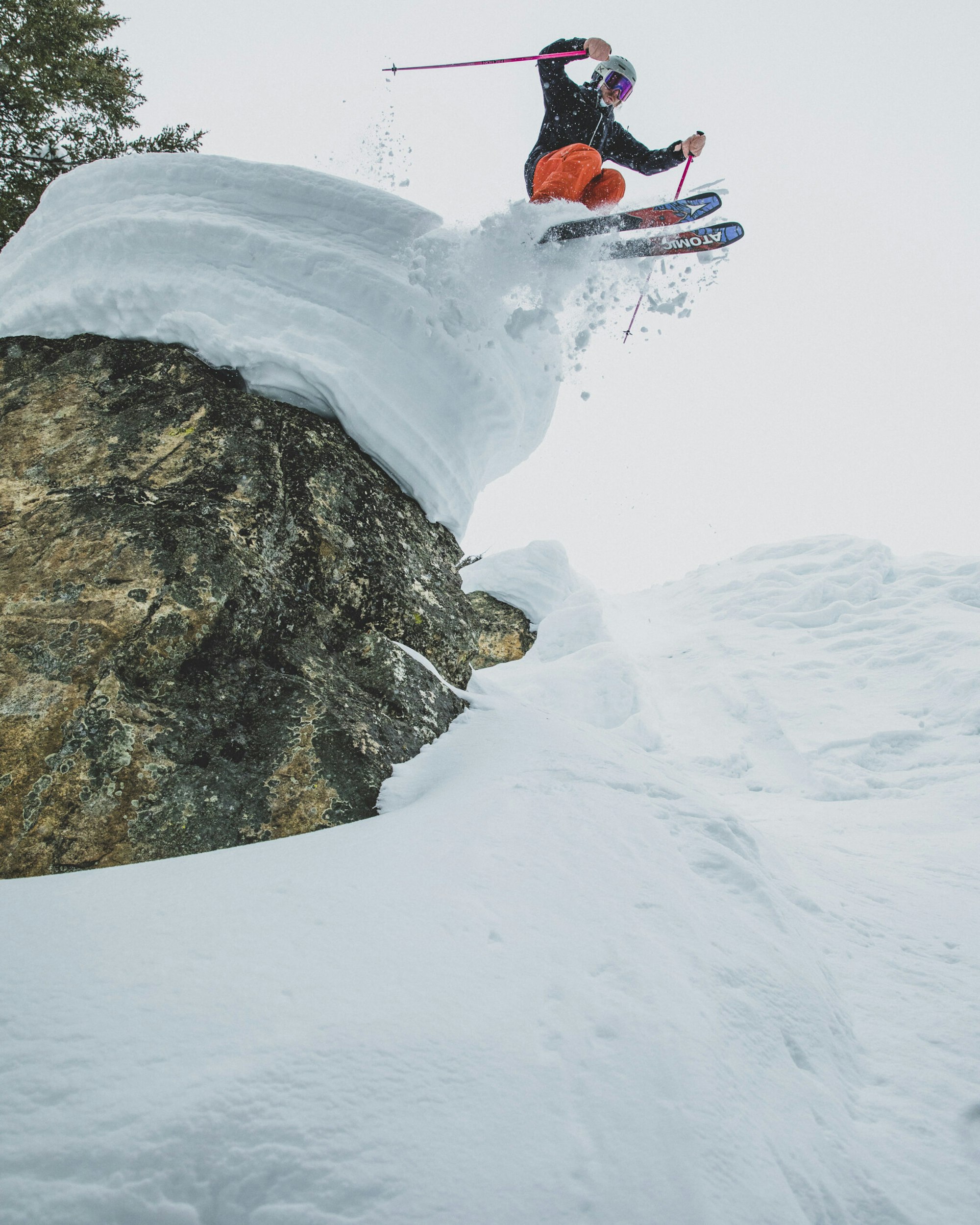 Skier jumping off a snowy rock into deep snow