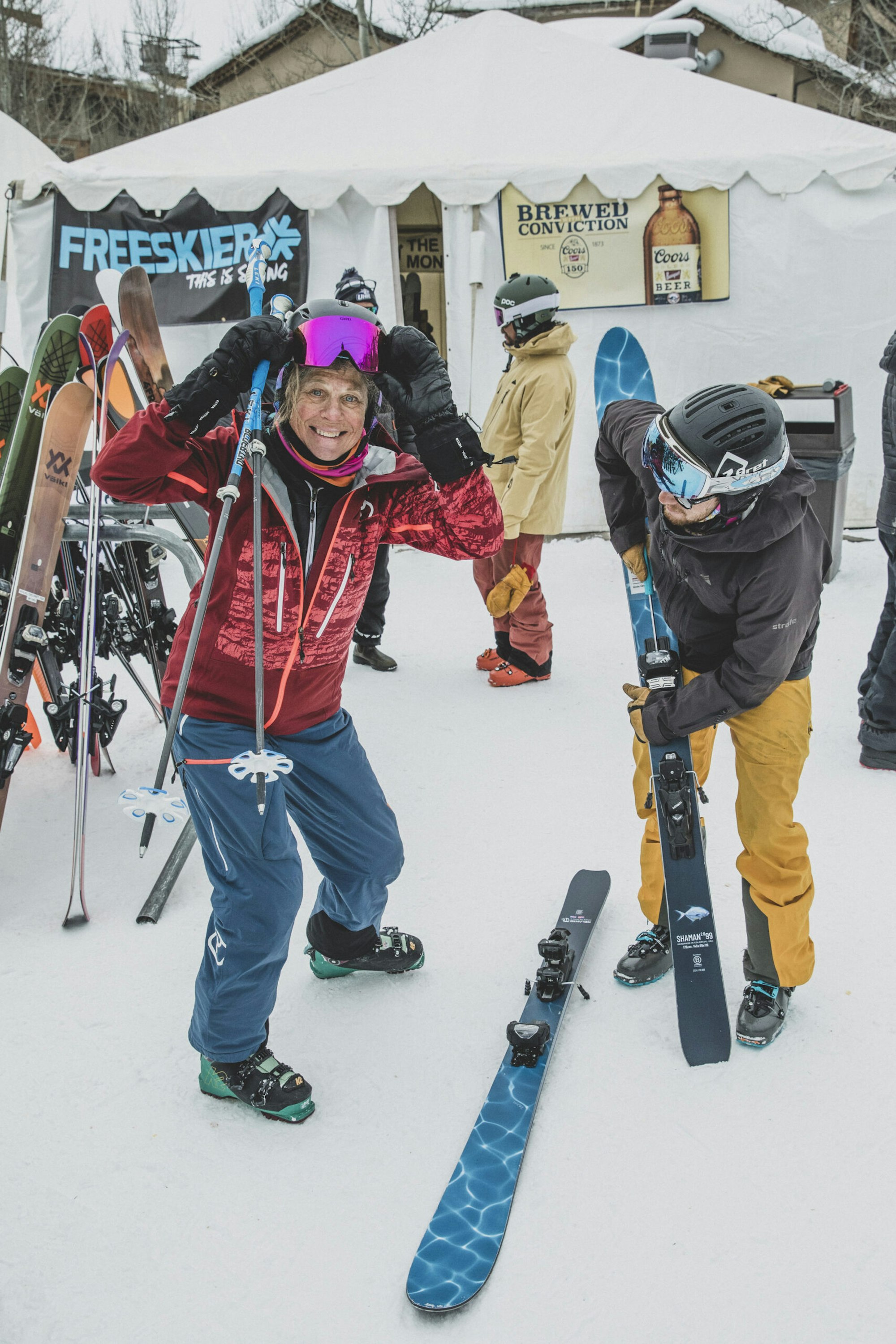 two skiers smile in front of a coors and FREESKIER branded tent