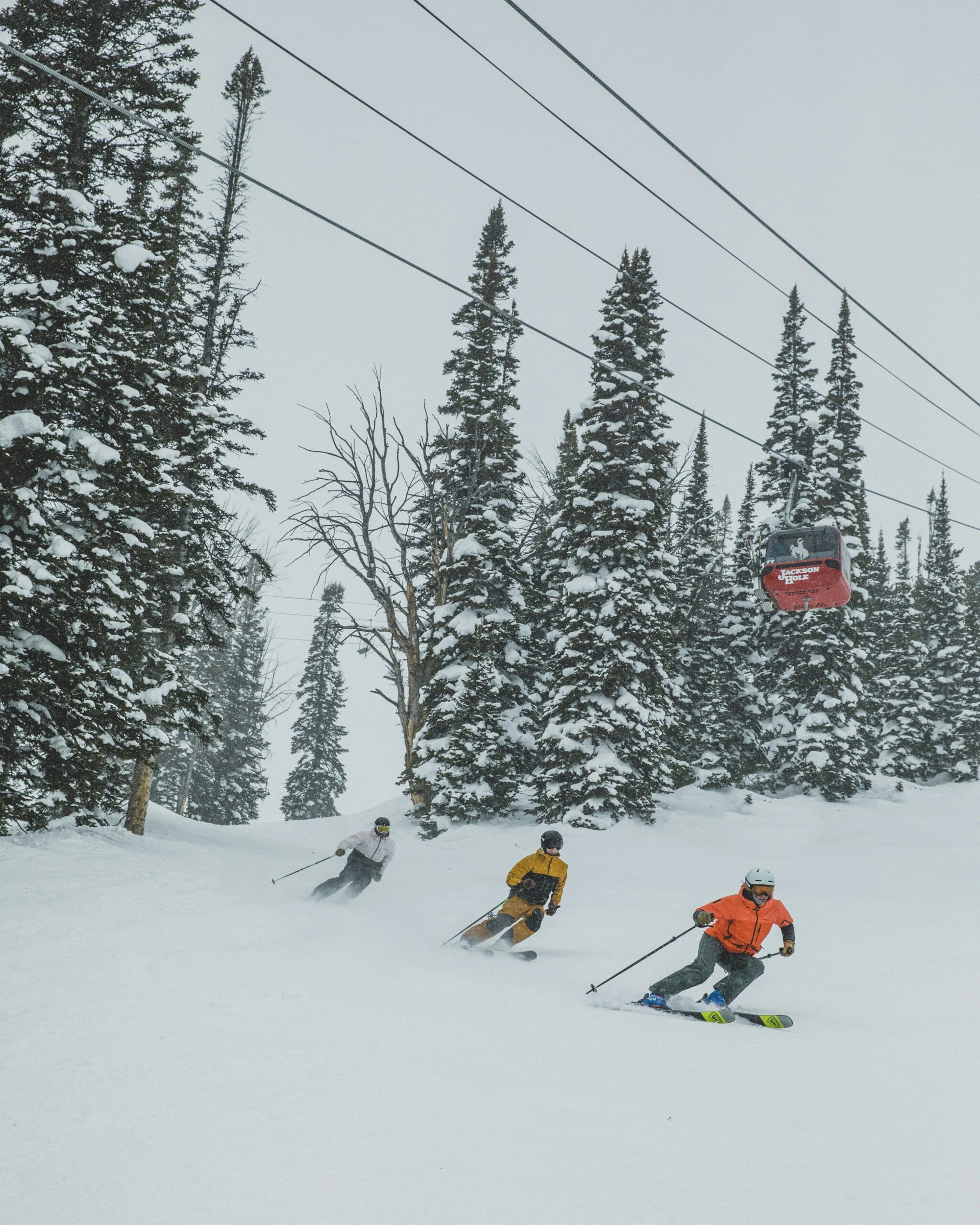 Three skiers ski below the Jackson Hole tram