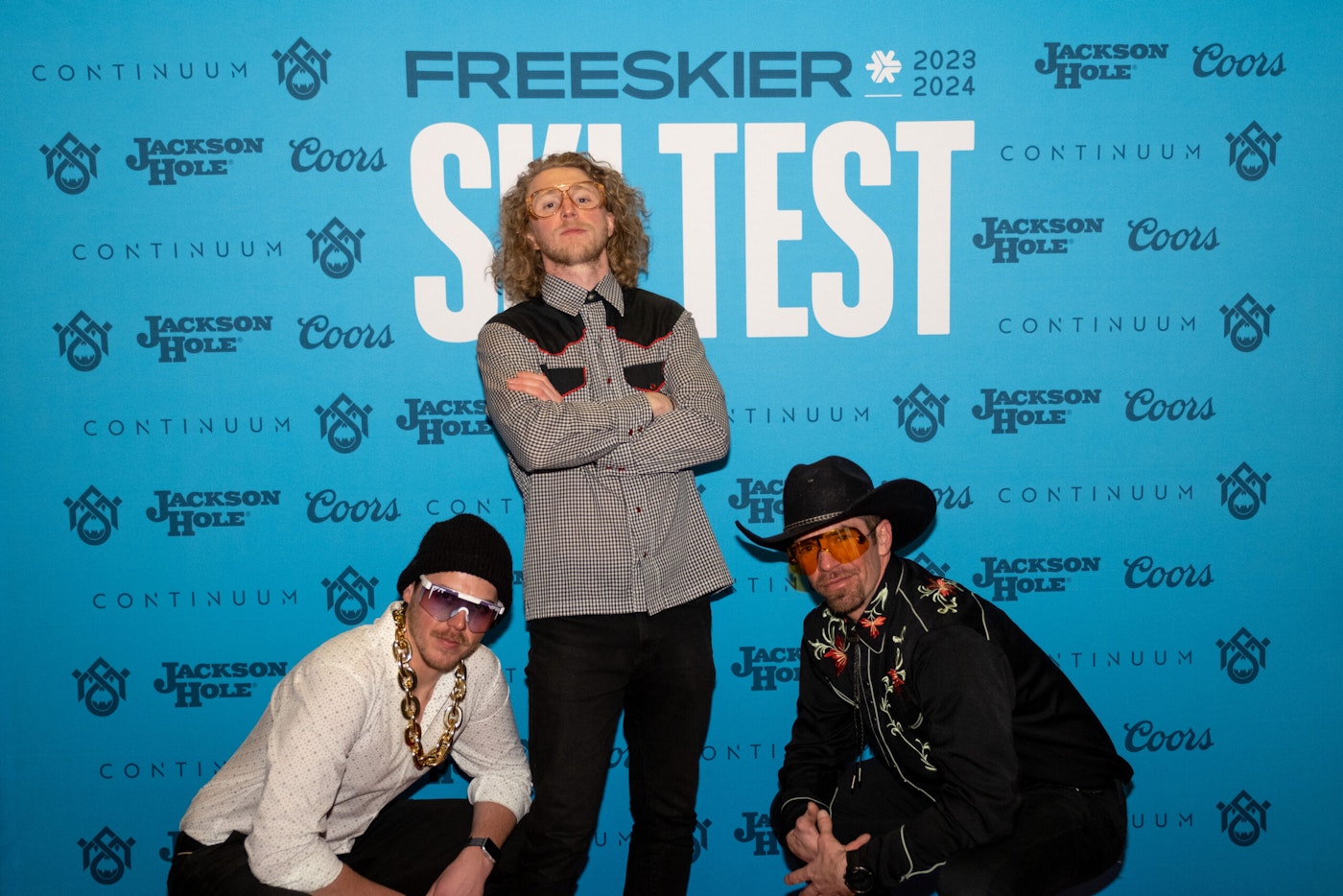 Three people pose in front of FREESKIER banner