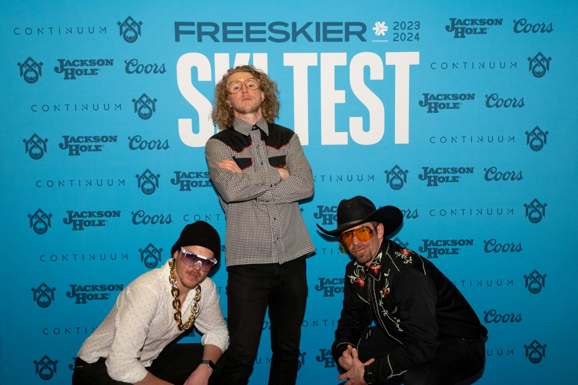 Three people pose in front of FREESKIER banner