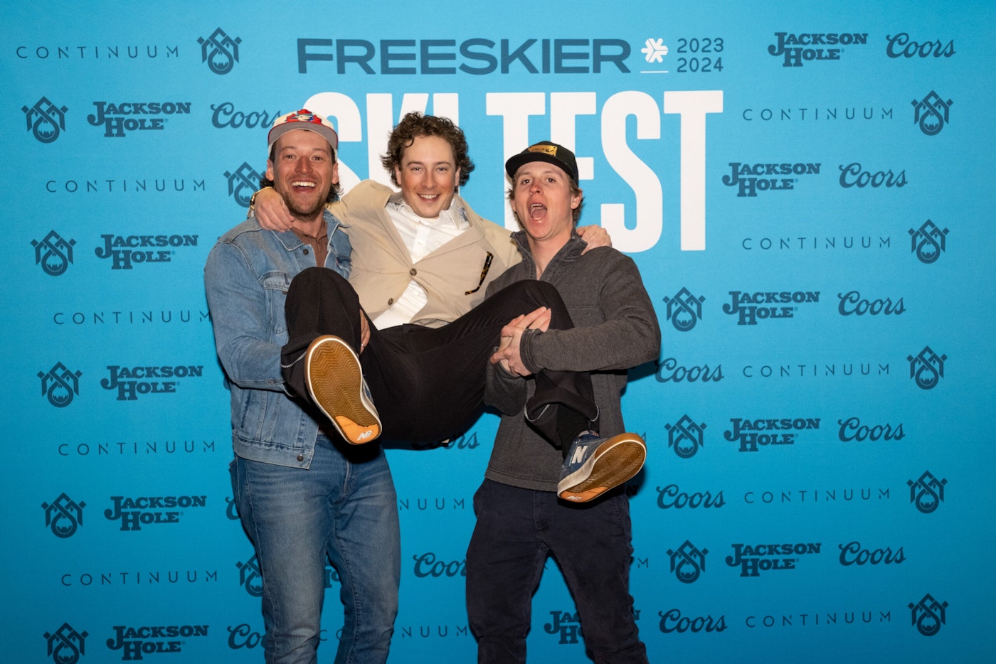 Three people pose in front of FREESKIER banner