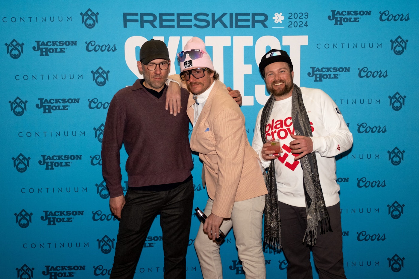 Three people pose in front of FREESKIER banner