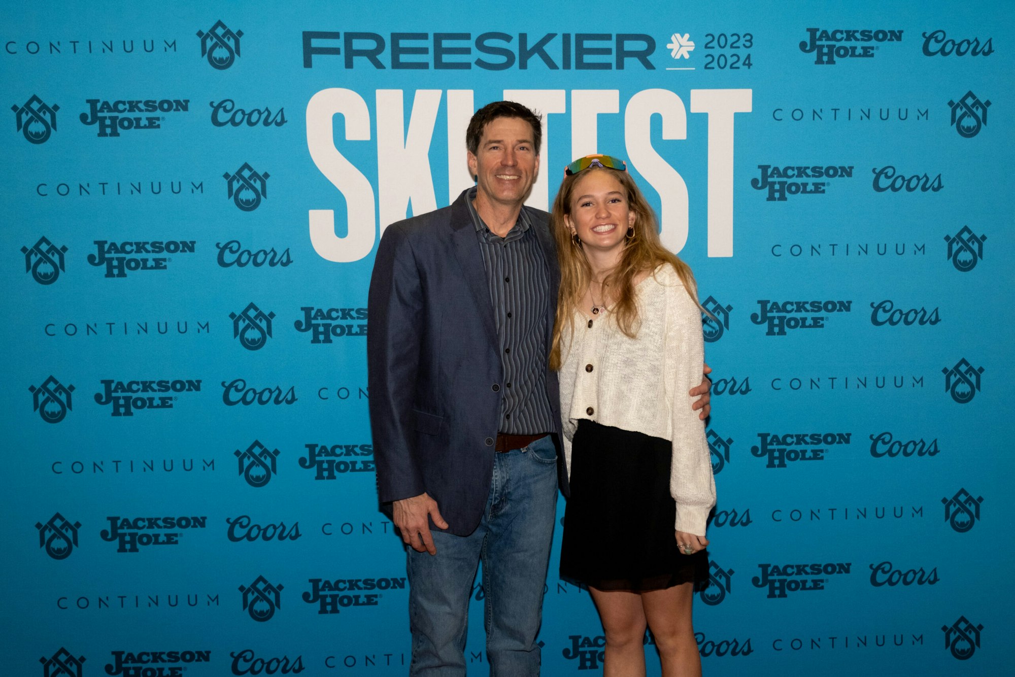 2 people pose in front of FREESKIER banner